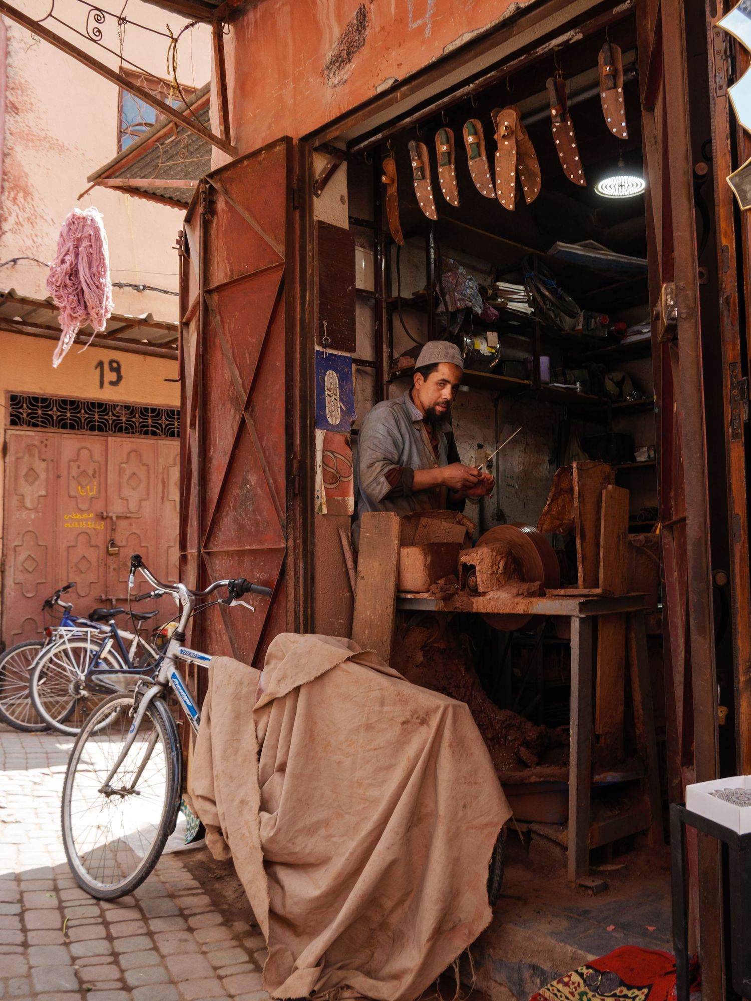 Craftsman working in a small traditional workshop in a narrow Moroccan medina alley.
