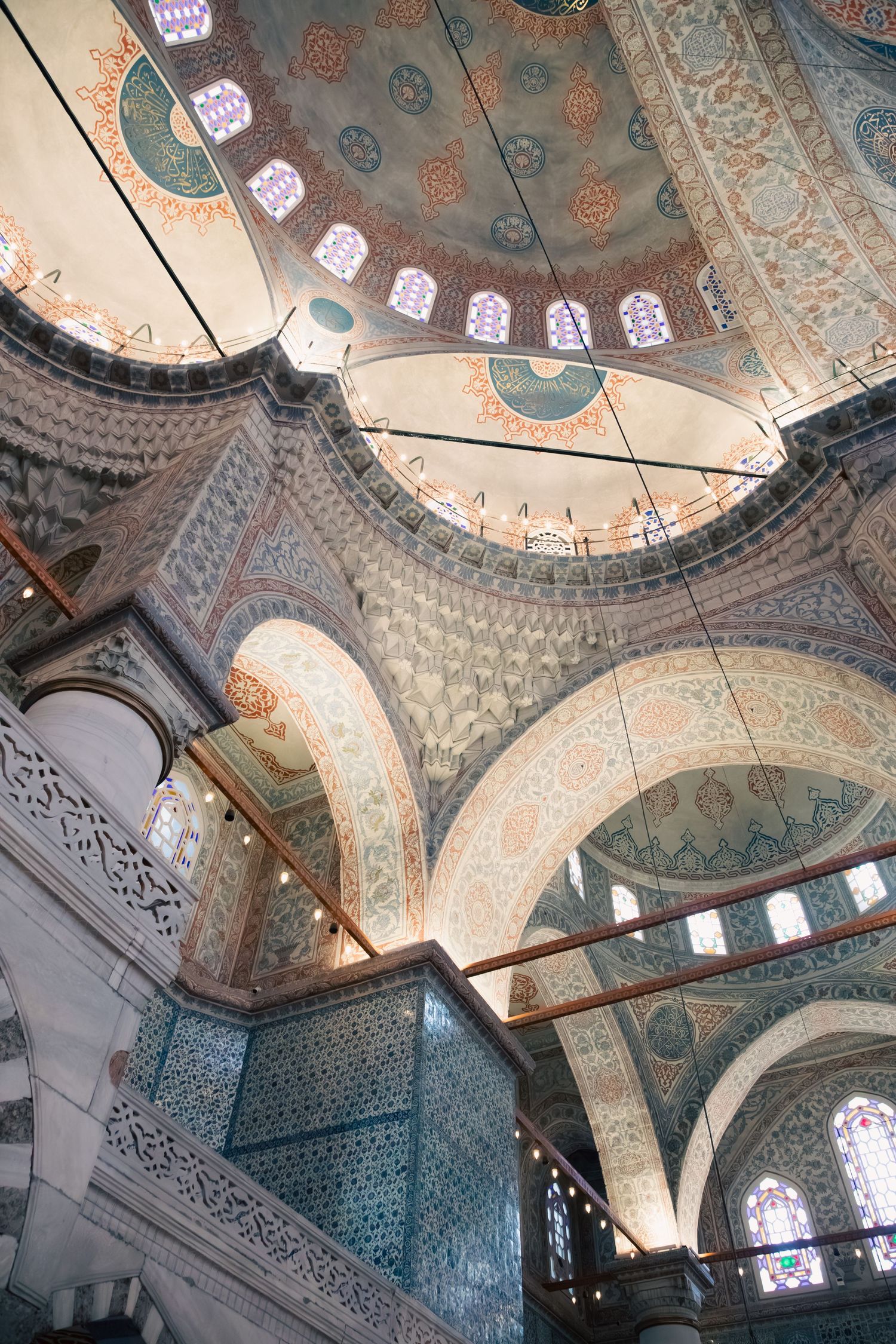 Ornate interior of the Blue Mosque in Istanbul featuring intricate tilework, arched domes, and stained glass windows.