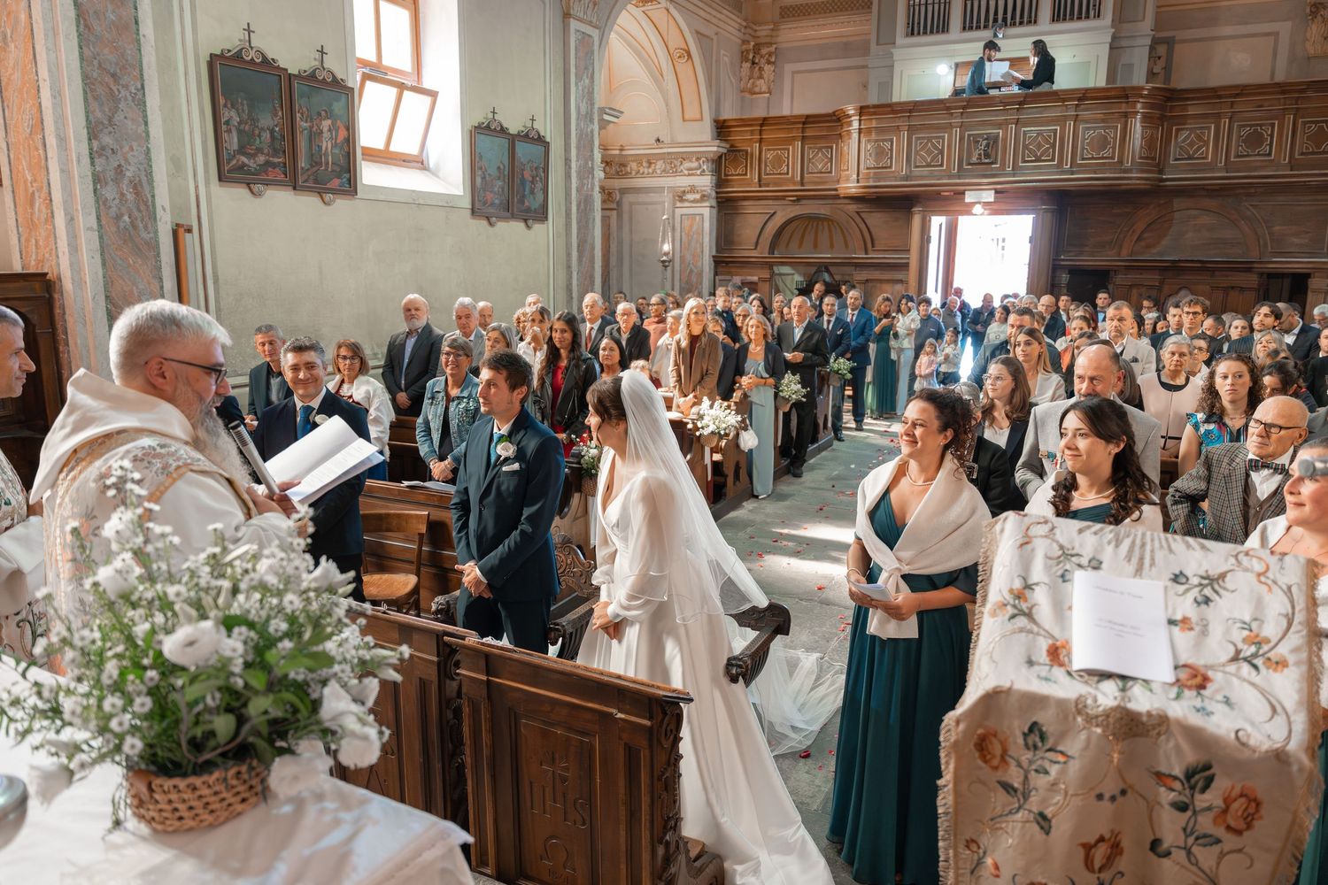 Bride and groom stand at altar during church wedding ceremony with teal bridesmaids.