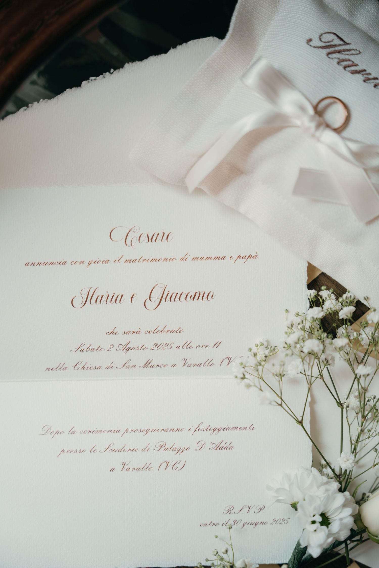 Elegant Italian wedding invitation for Maria e Giacomo with gold script, white flowers, and wedding rings.