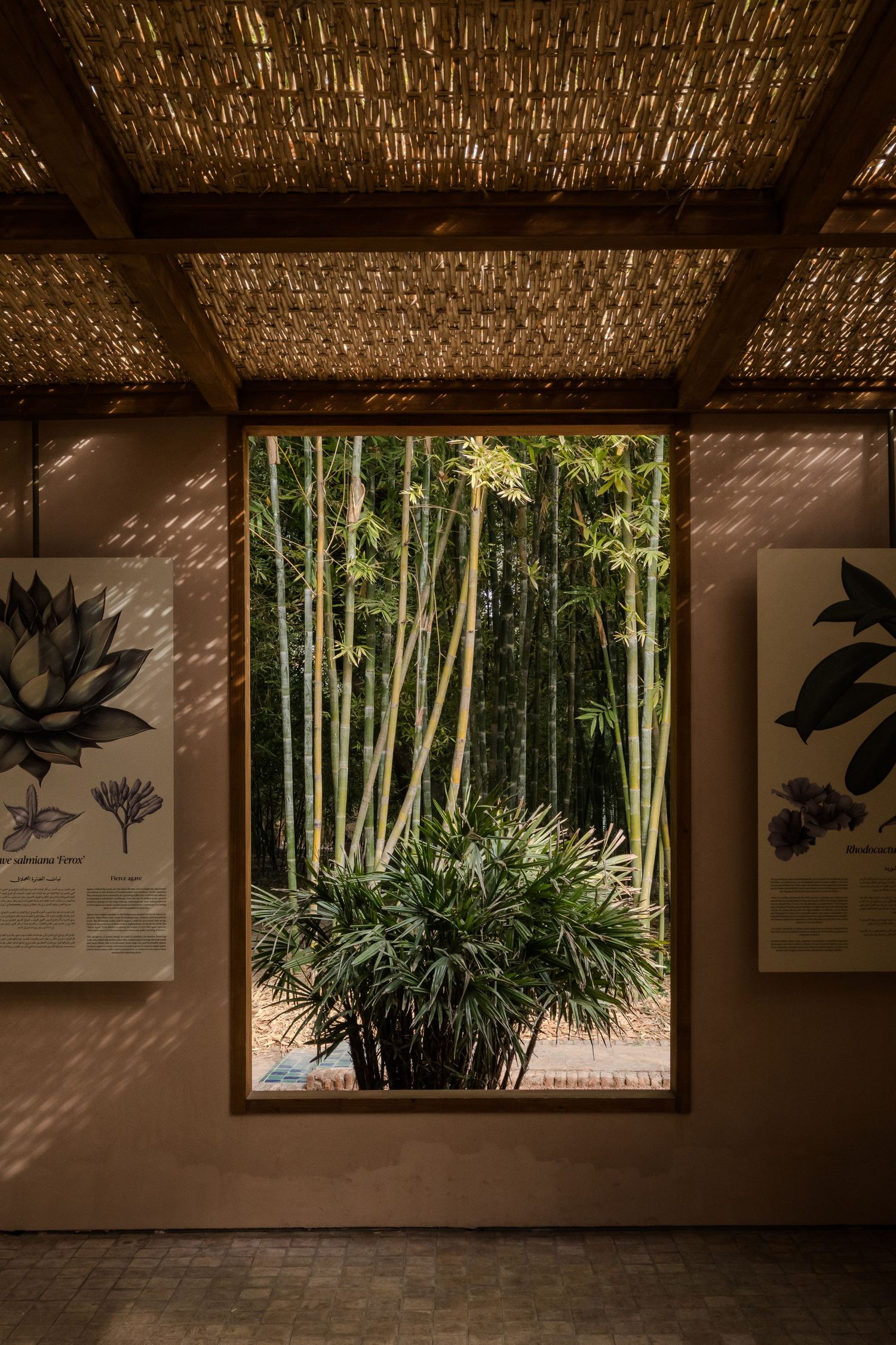 Bamboo forest viewed through a large wooden frame window in a tropical garden pavilion.