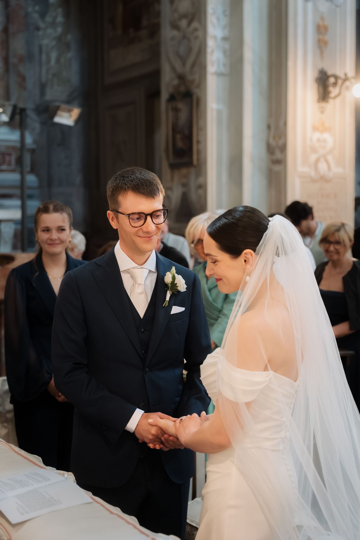 Bride and groom exchange vows holding hands at a grand church altar during wedding ceremony.