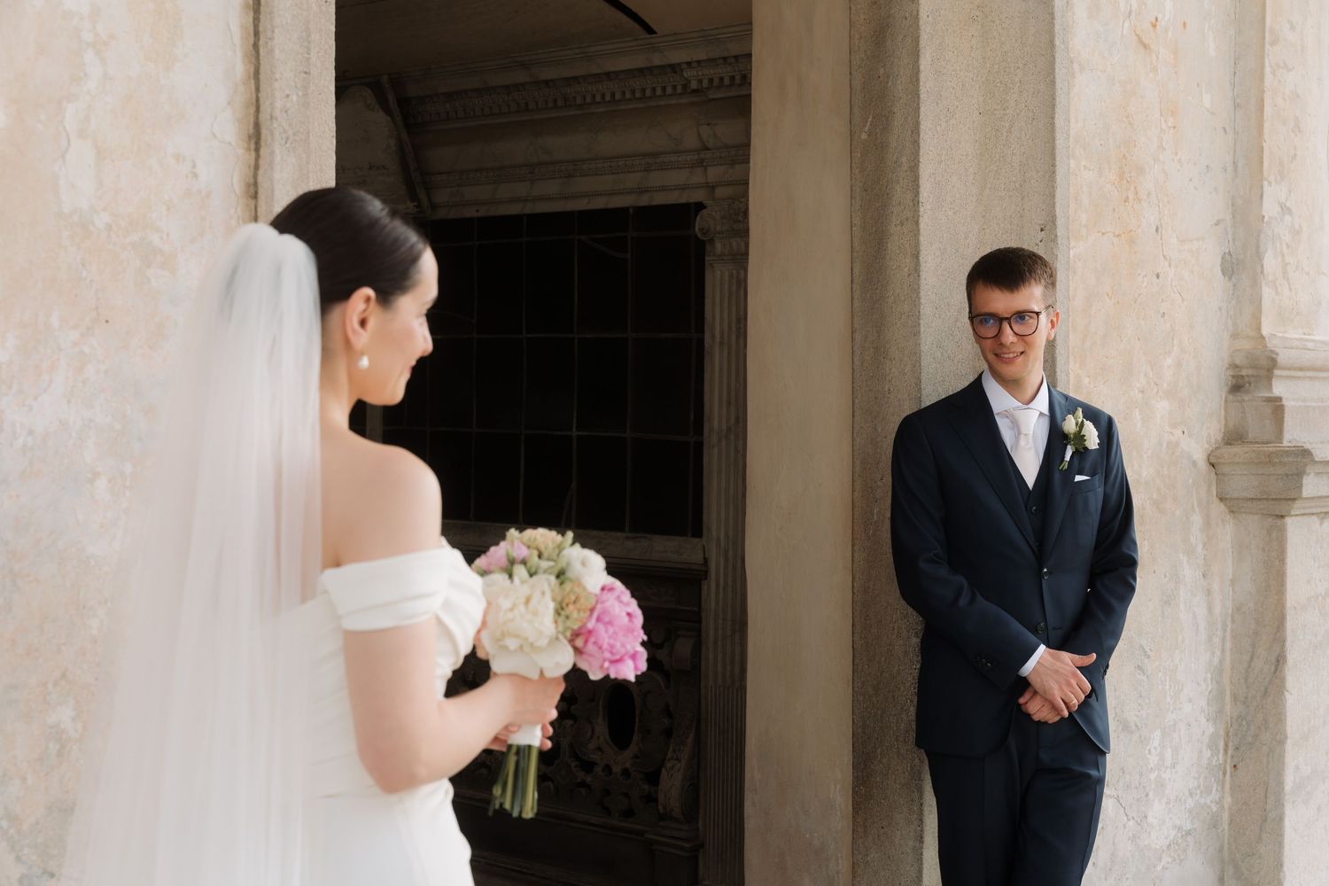 Groom smiles seeing his bride for the first time in a classic wedding first look moment.