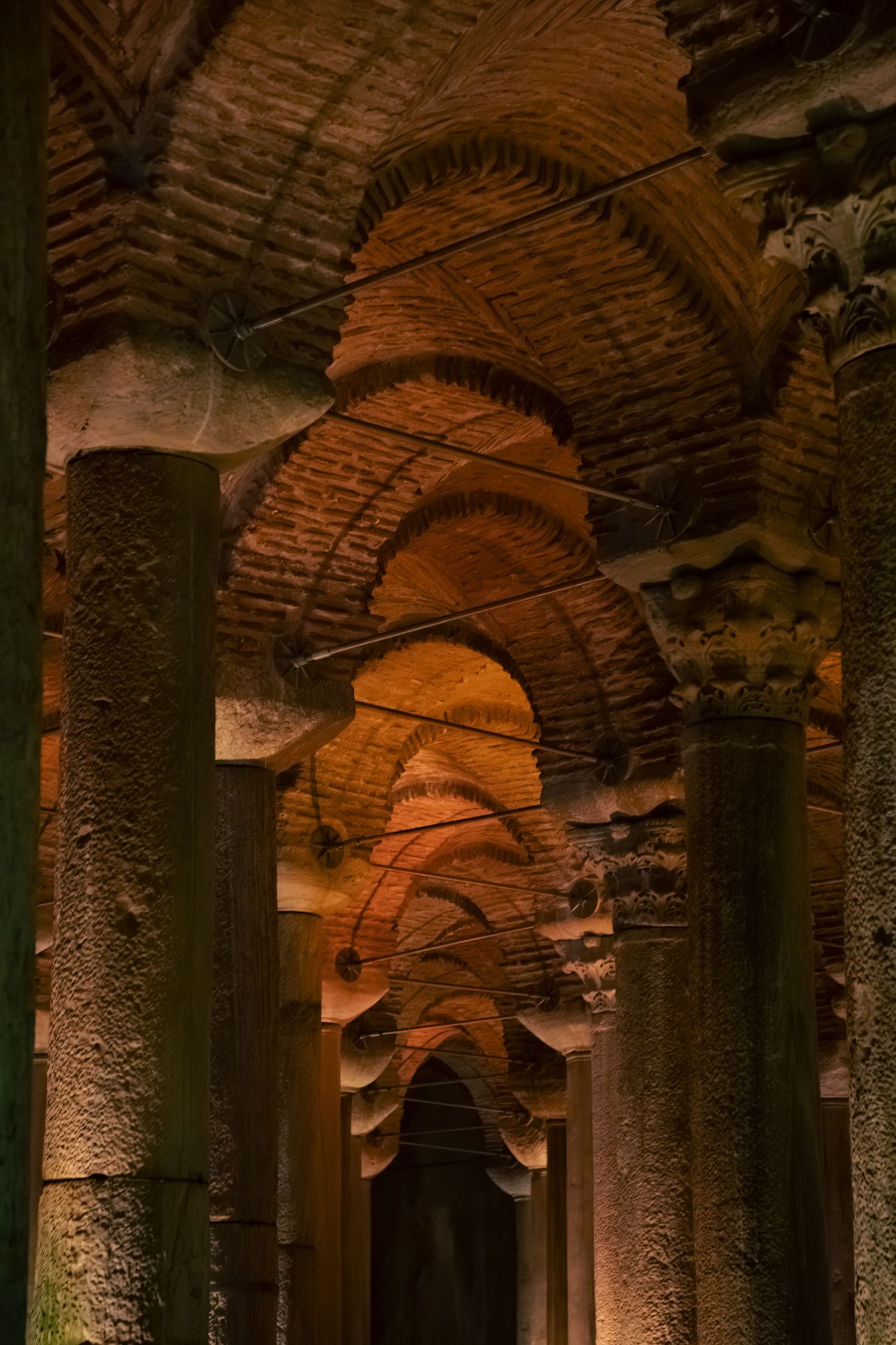 Ancient underground Basilica Cistern in Istanbul with illuminated brick arches and stone columns.