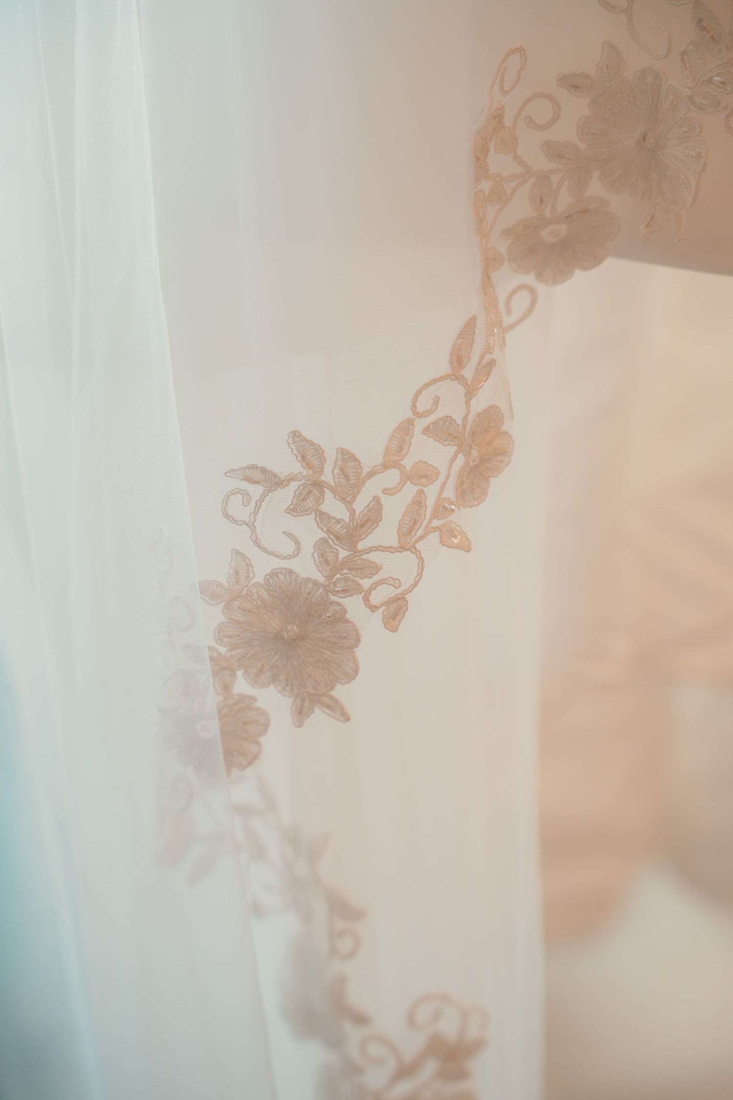 Close-up of delicate floral embroidery detail on sheer white bridal veil fabric.