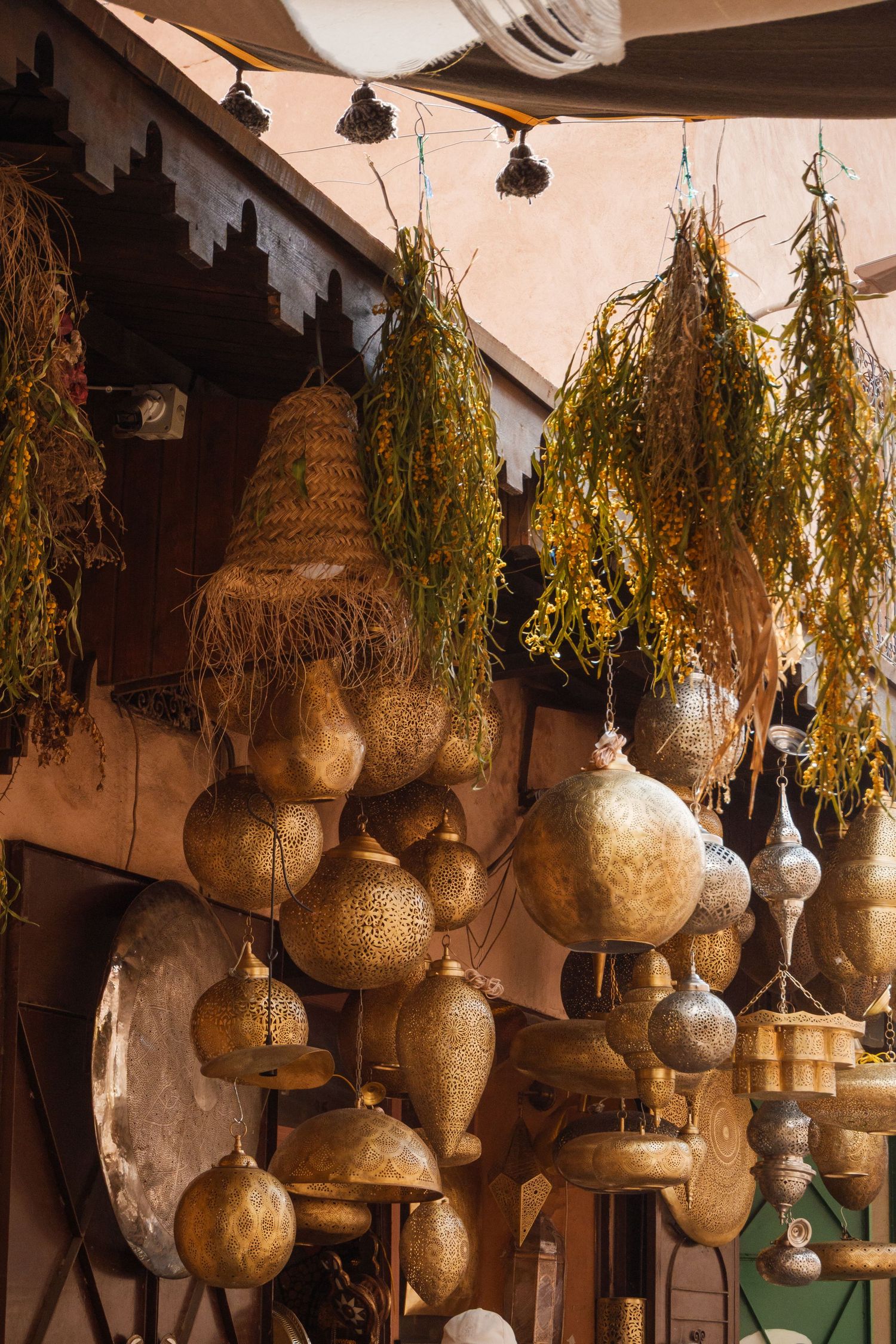 Golden Moroccan lanterns and dried herbs hanging outside a traditional souk market stall.