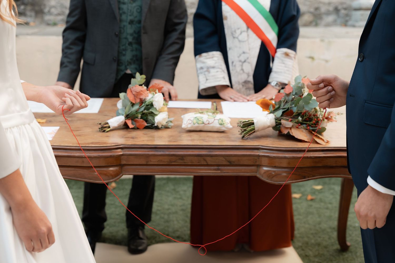 Wedding signing table with bridal bouquets and officiant sash during an Italian civil ceremony.