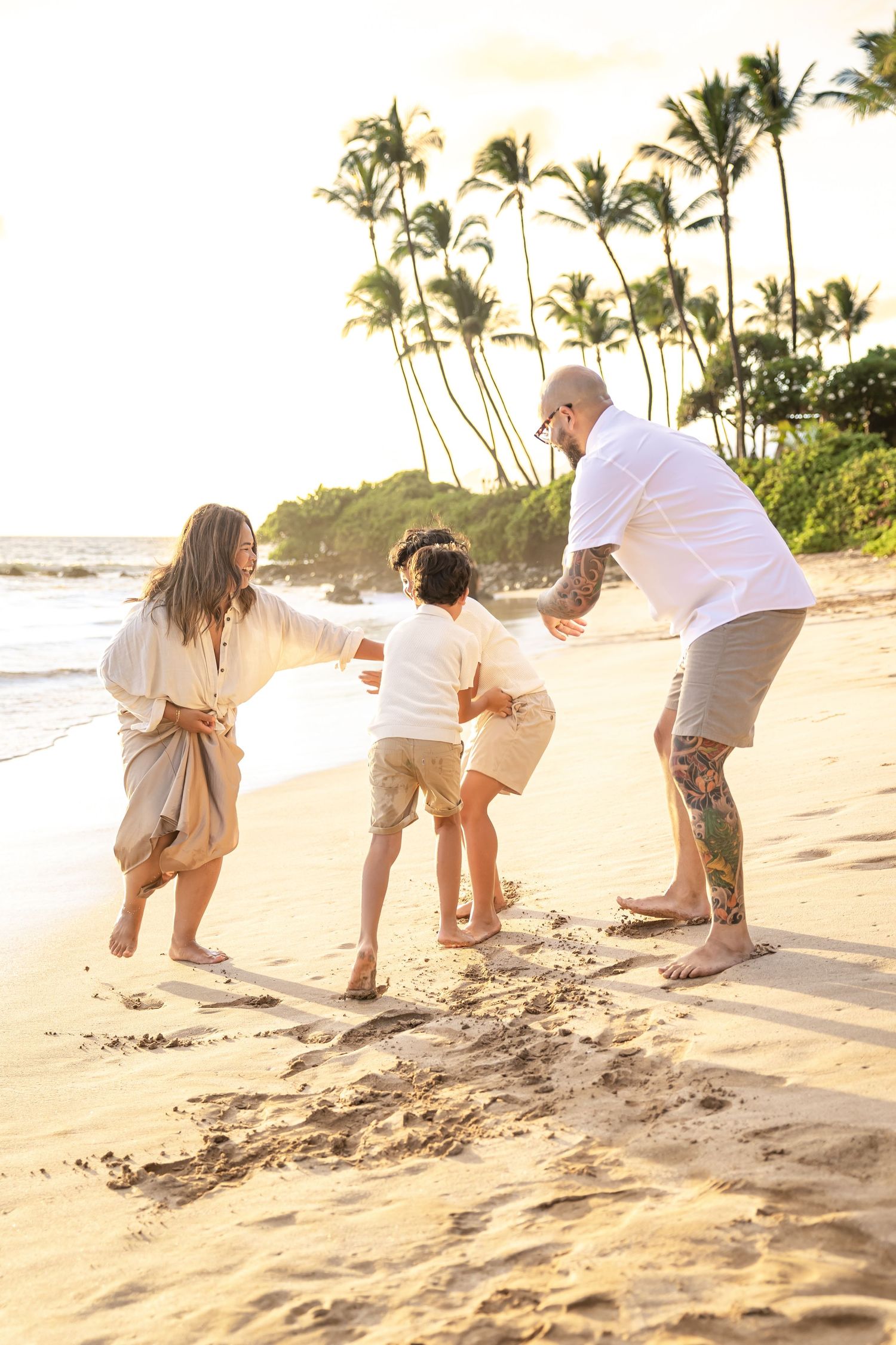 Joyful family playing together on a sunny Hawaiian beach with palm trees.