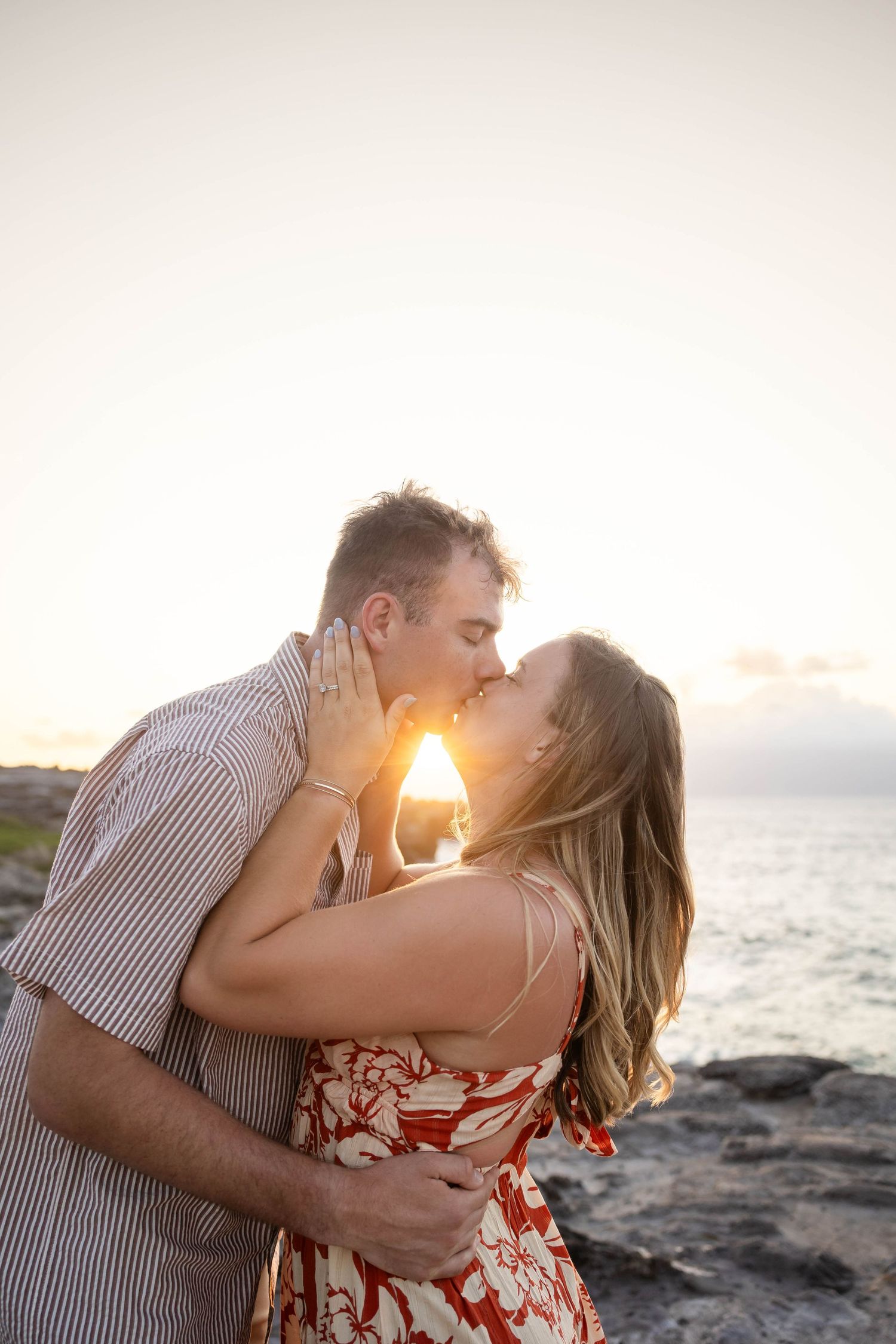 Couple sharing a romantic kiss at golden hour by the ocean.
