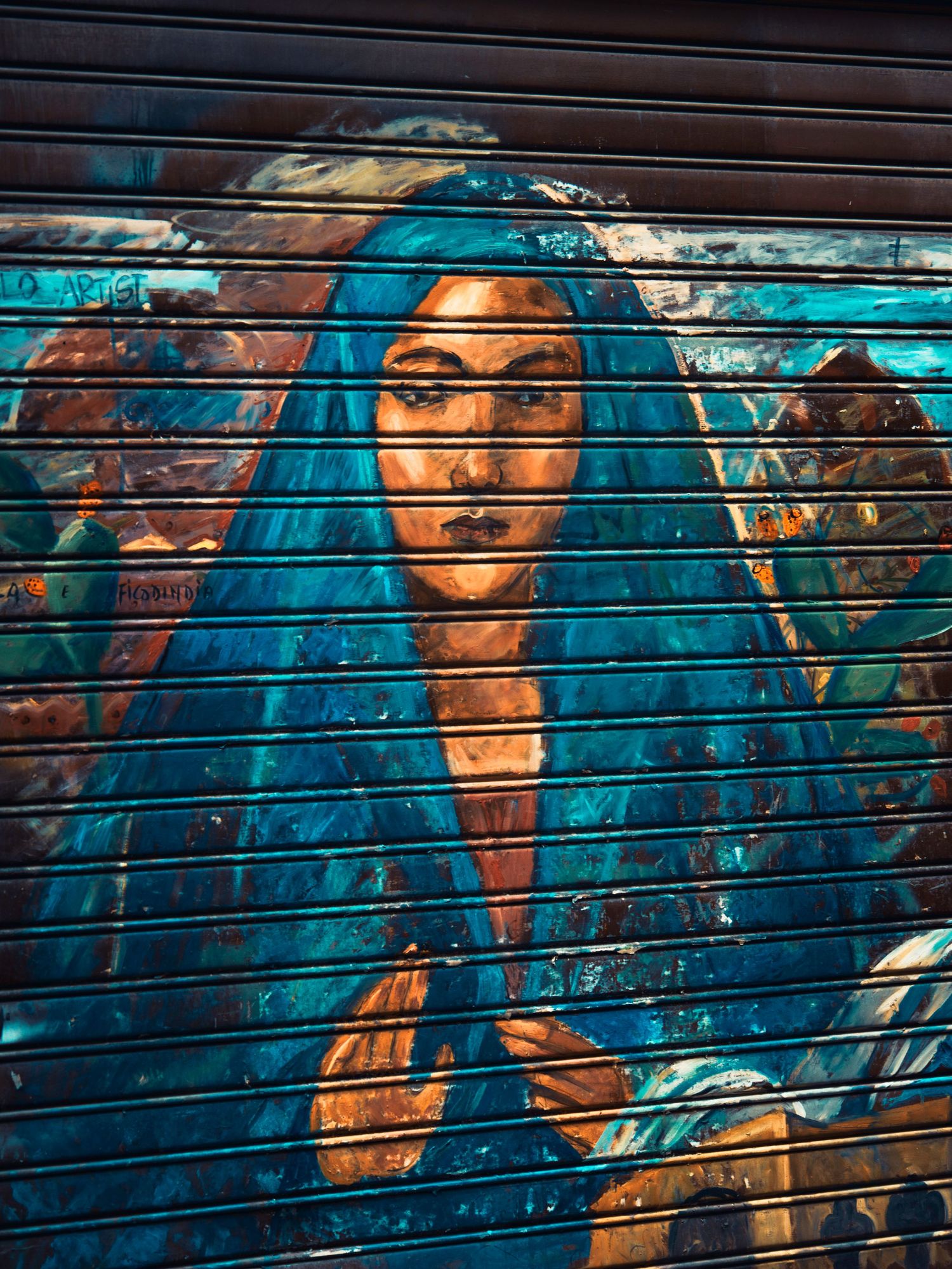 Vibrant street art mural on a metal security gate features figures in turquoise and orange tones against a dark background.