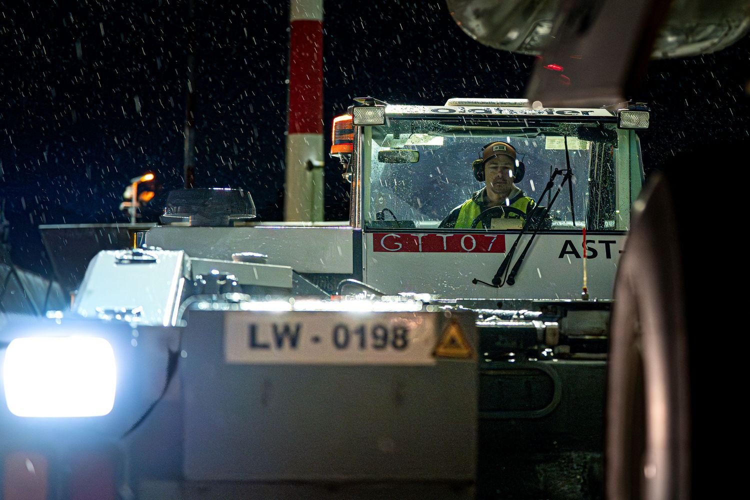 Aircraft tow vehicle illuminated at night during rainy weather conditions.