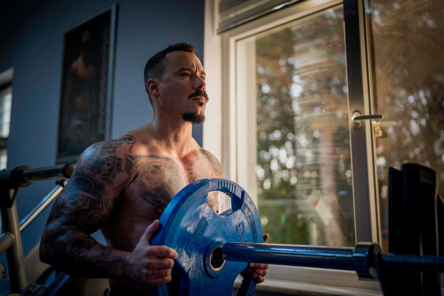 A dramatic portrait photo showing a muscular bodybuilder racking his weights on a bench press bar.