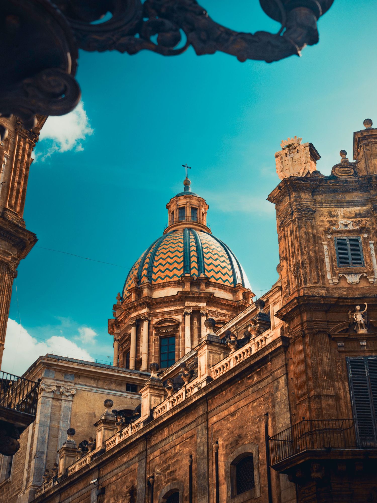 Ornate baroque dome and architectural details of a historic cathedral in Sicily against vibrant turquoise sky.