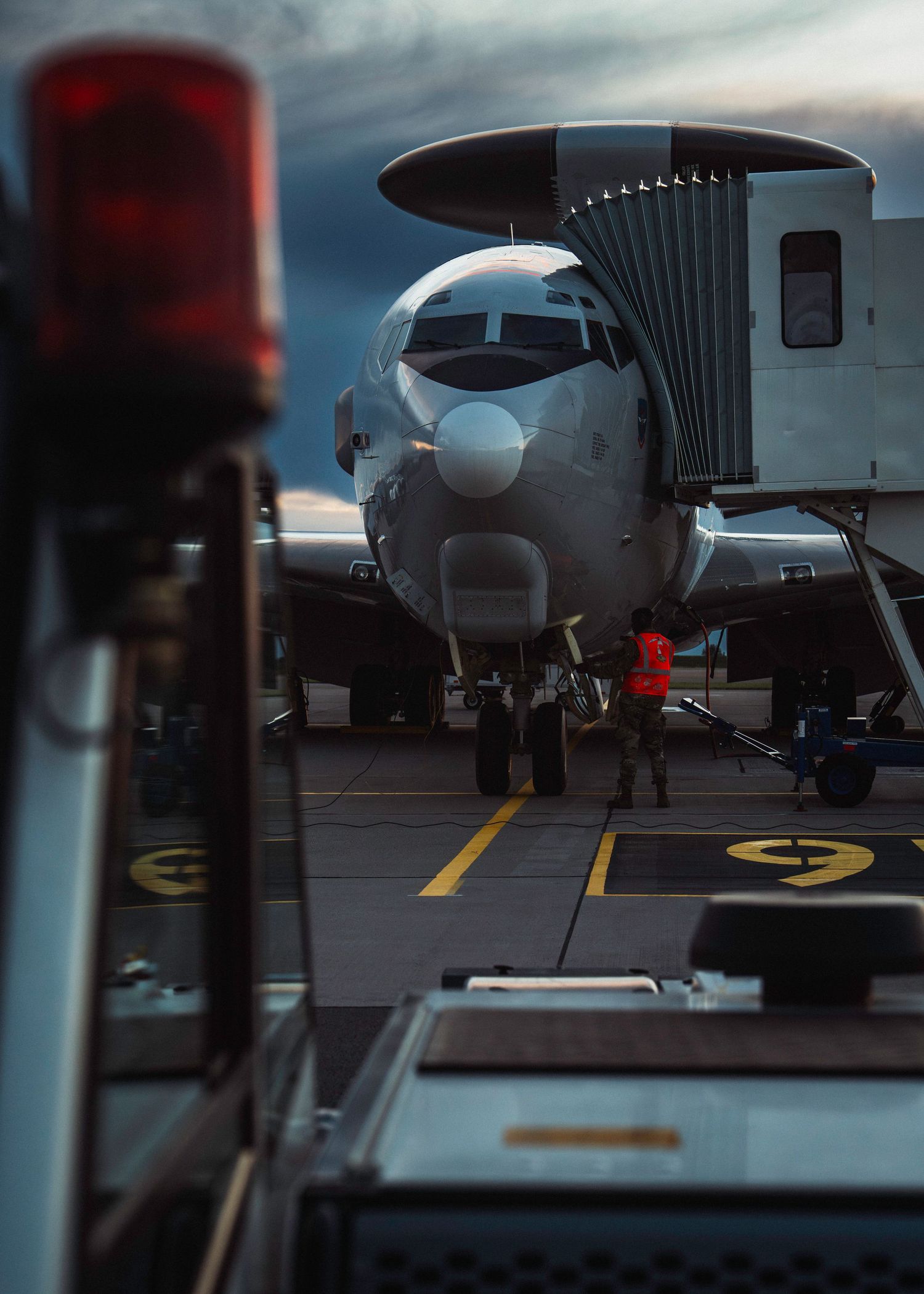 A NATO AWACS E-3A Sentry parked on a tarmac with dark clouds in the background during sunset.