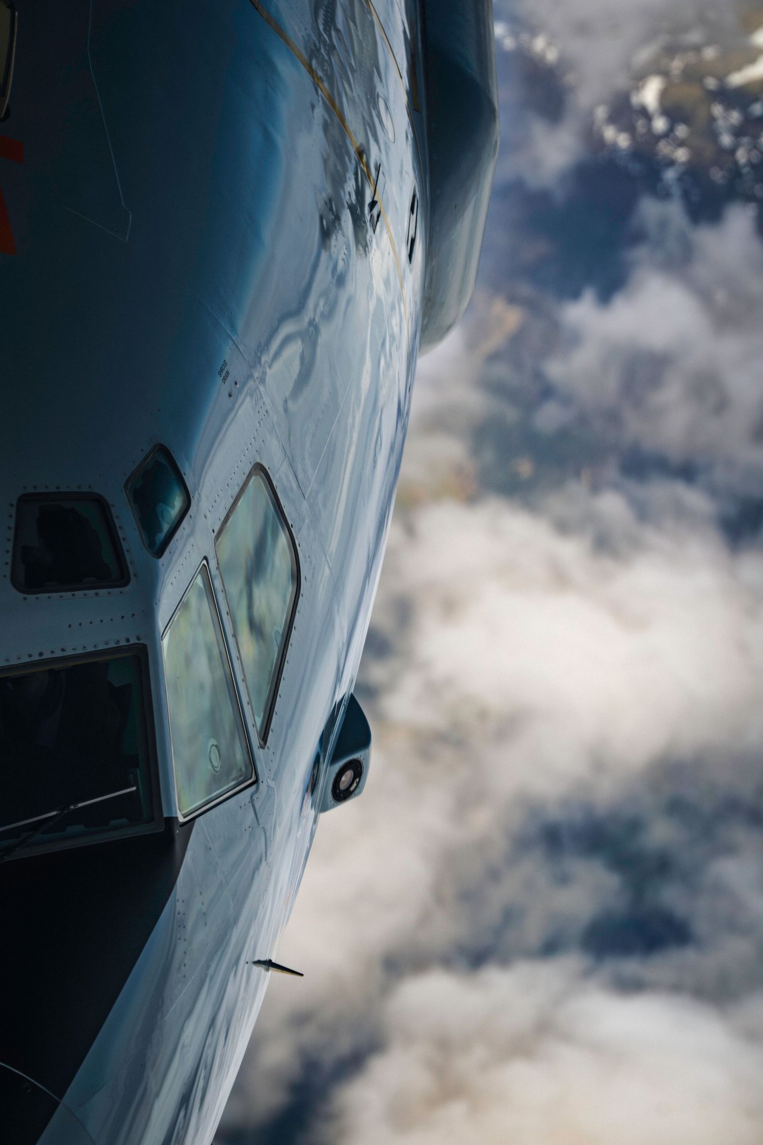 Close-up view of an aircraft fuselage and window against a dramatic cloudy sky background.