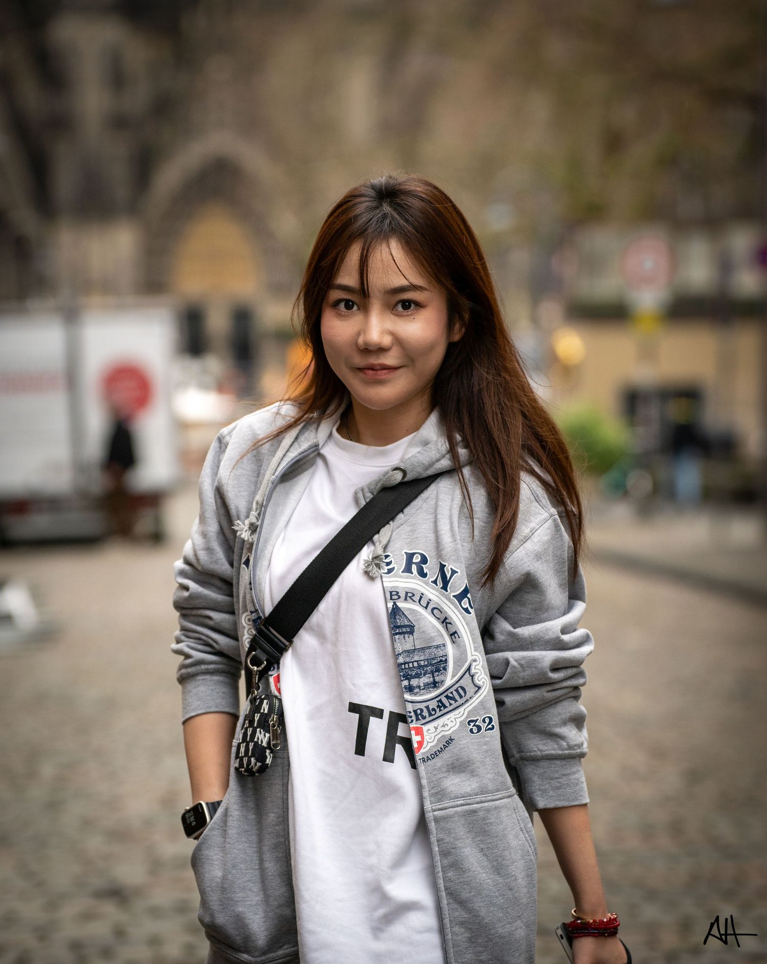 Street-style portrait of a person wearing a grey sweatshirt layered over a white t-shirt.