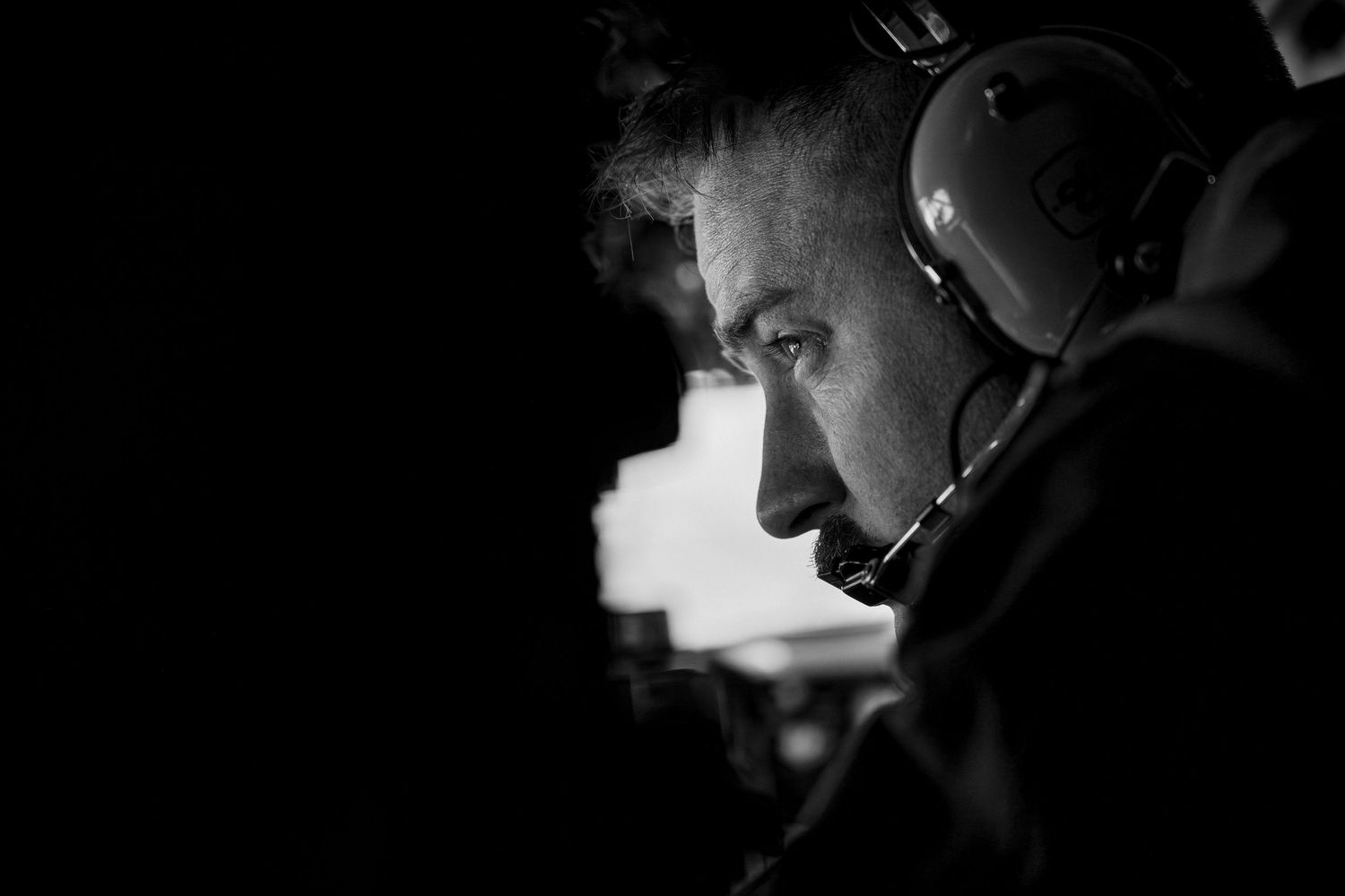 Black and white photo showing a KC-135 Stratotanker Boom Operator looking out an aircraft window.