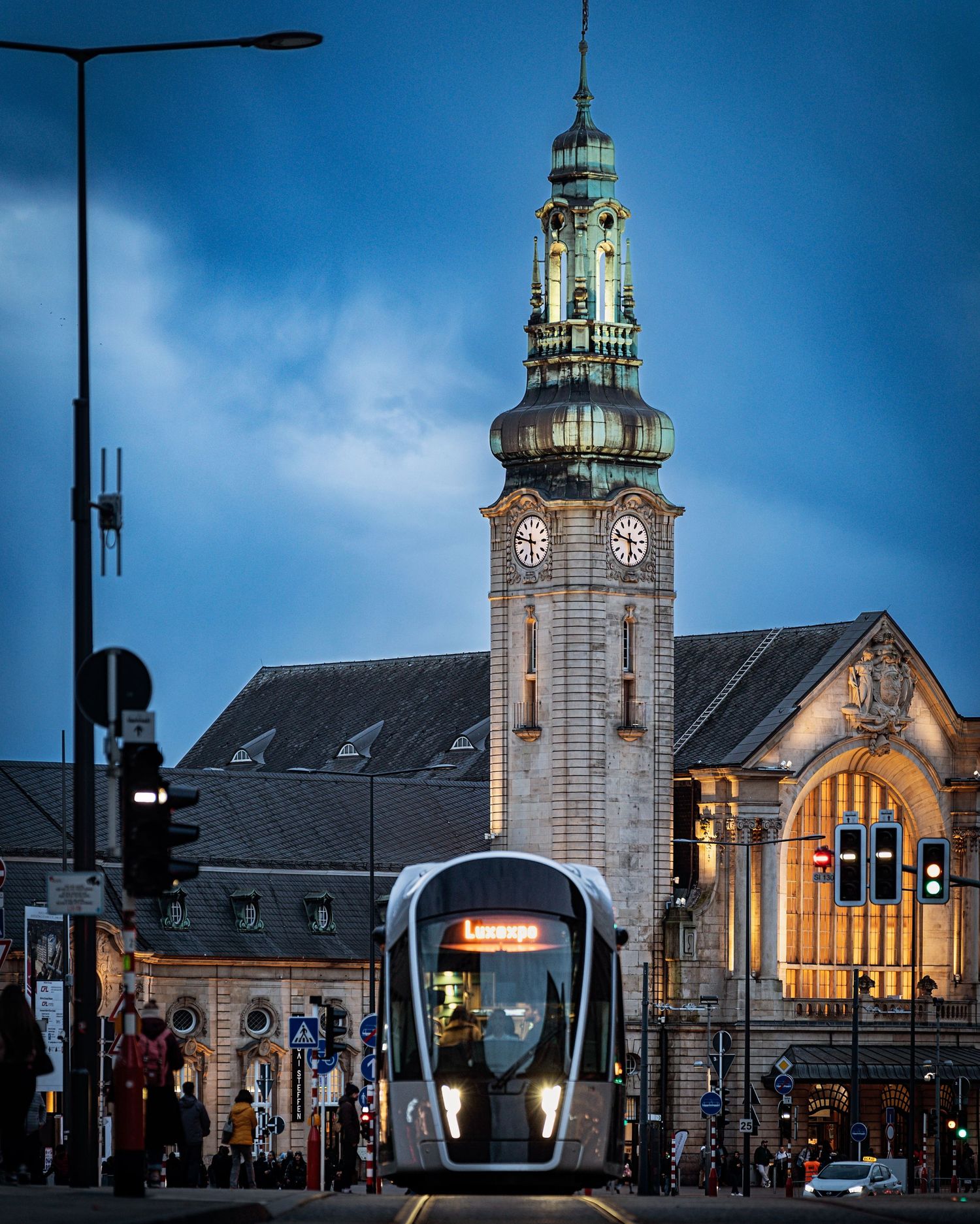 Architectural photograph of a clock tower in Luxembourg with a tram in the foreground.