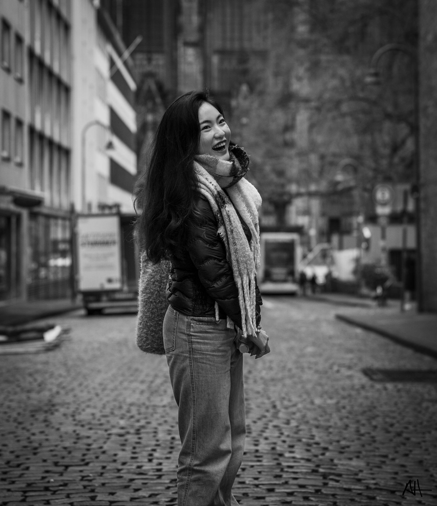 Black-and-white portrait of a woman standing on a city street.