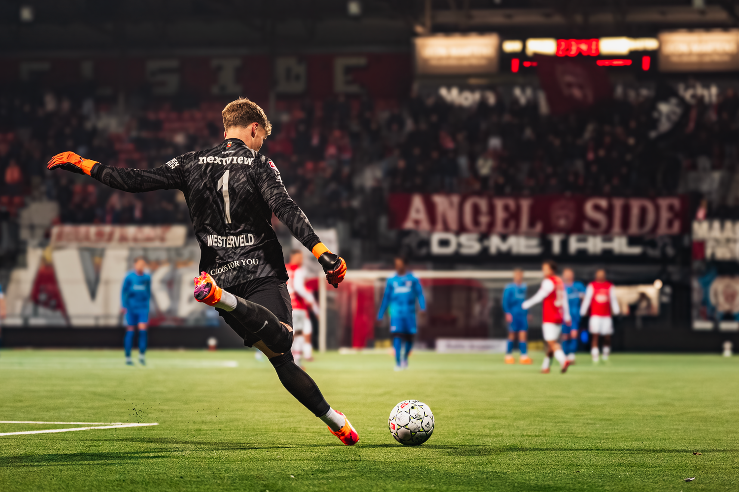 Soccer goalkeeper takes a free kick during a match in a floodlit stadium in the Netherlands.