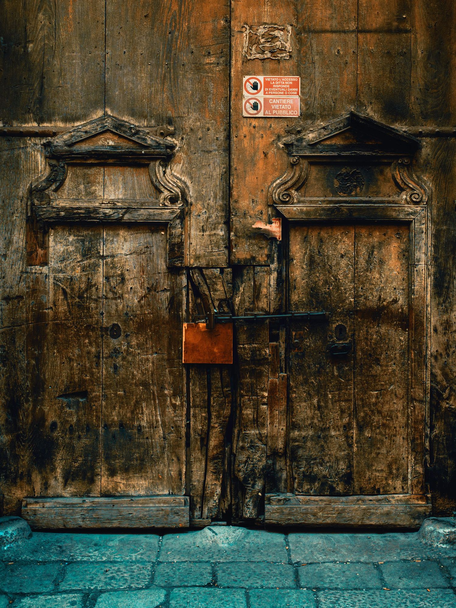 Old wooden doors with decorative architectural elements and turquoise base features weathered textures and ornate details.