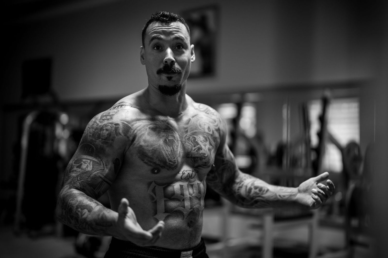 Black and white photo series showing a muscular tattooed person working out in a gym with various exercises.