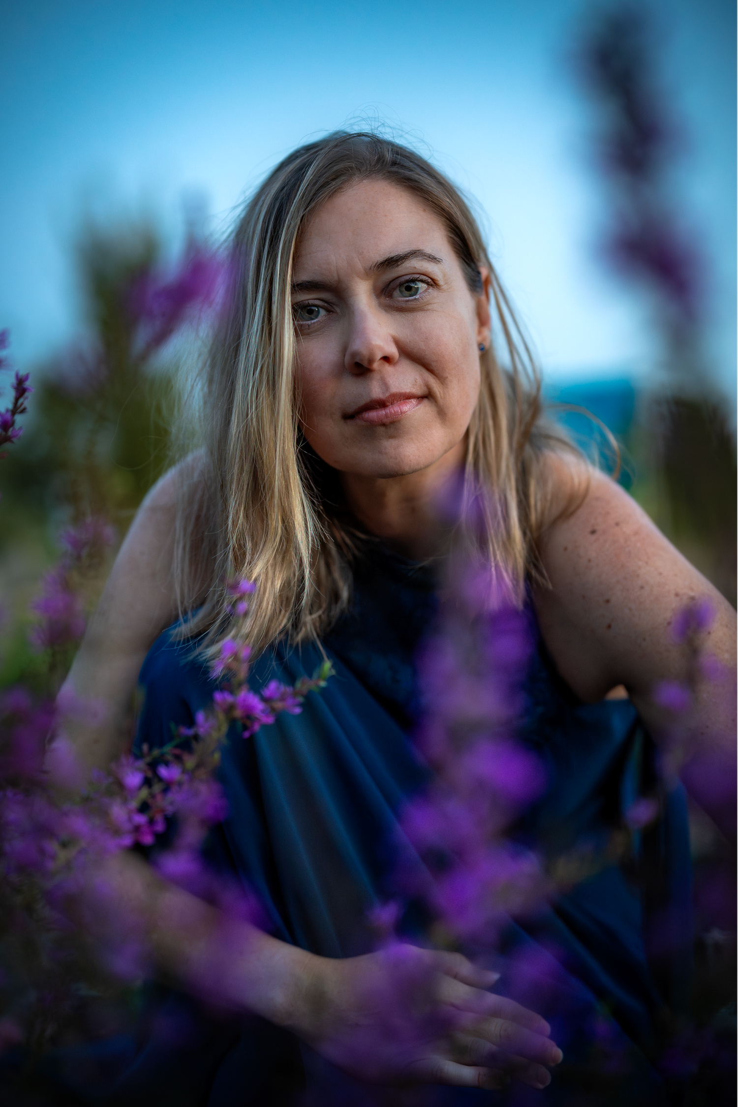 A series of outdoor portrait shots with purple flowers in the foreground creating a dreamy bokeh effect.