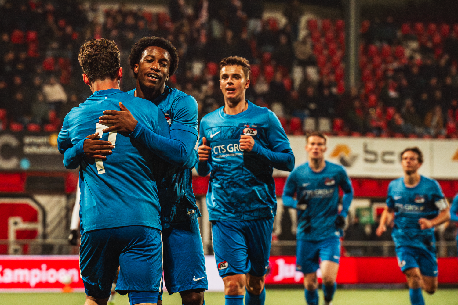 Soccer players in blue jerseys celebrate together after scoring a goal during a match.