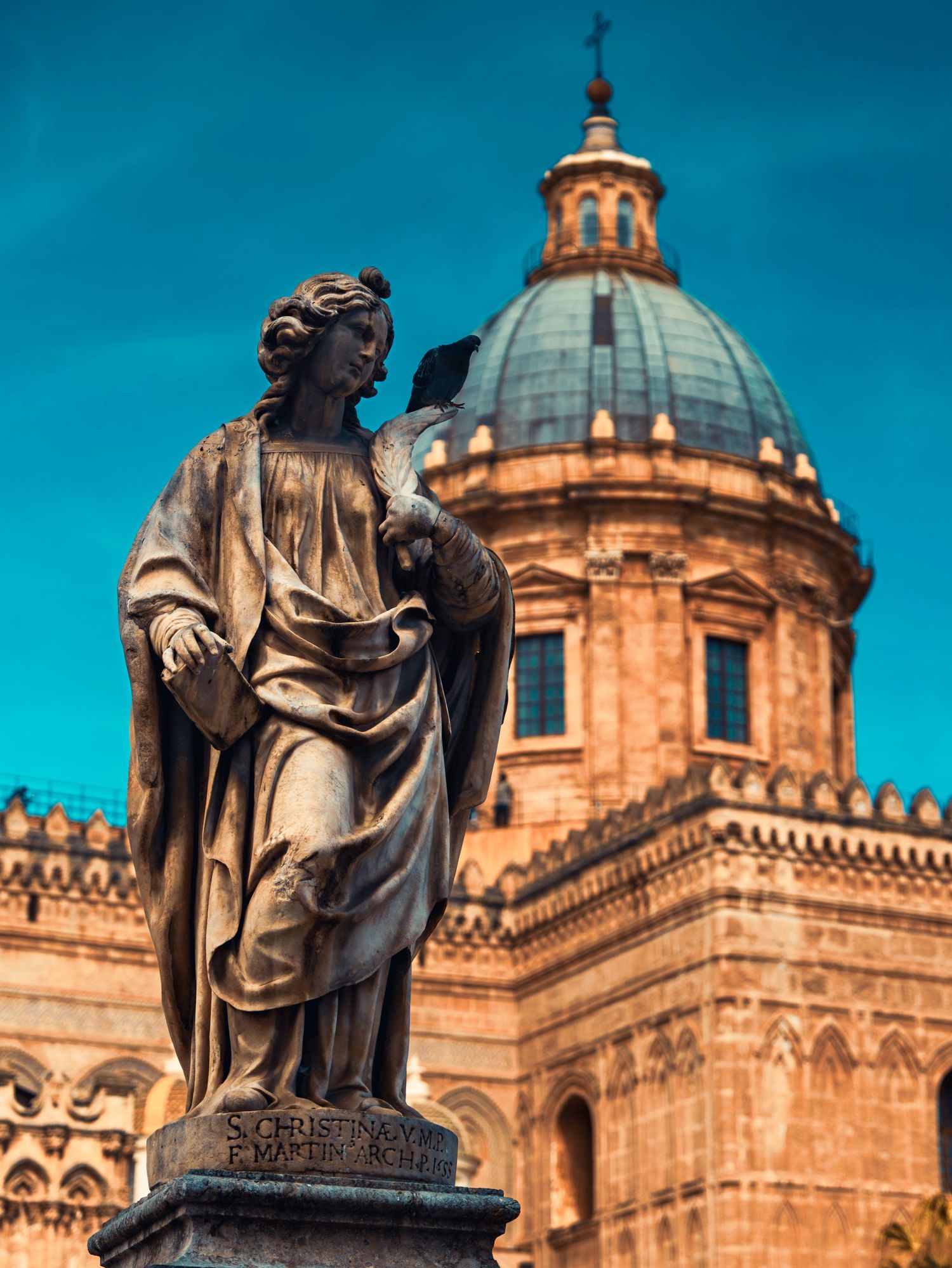 Historic stone statues and domed architecture of Cusco Cathedral against vibrant blue sky in Peru.