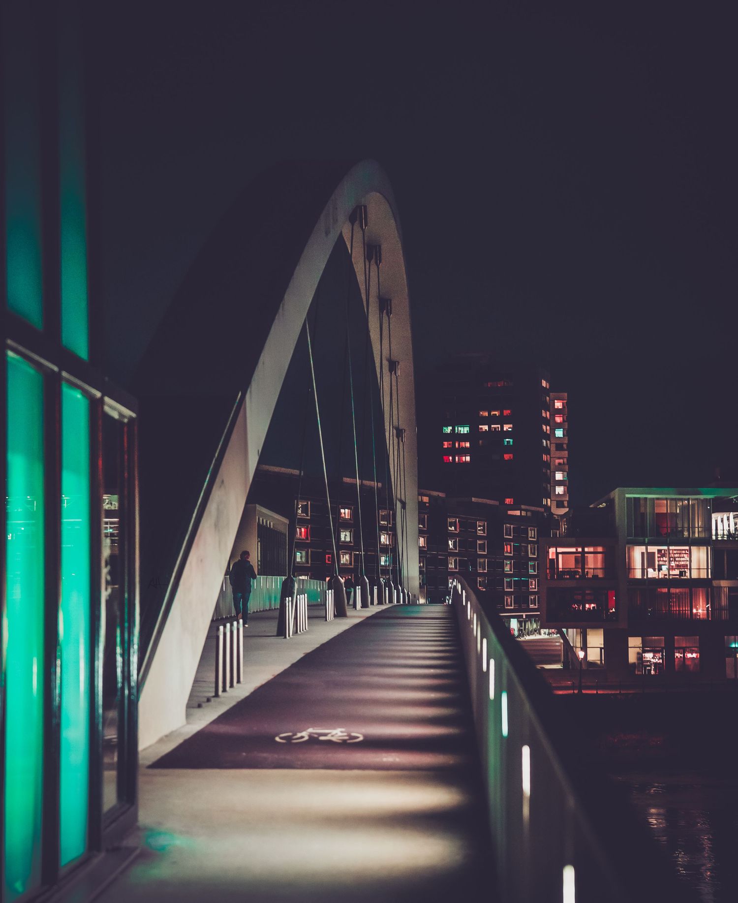Nighttime photograph of a pedestrian bridge in Maastricht, illuminated by artificial lighting.