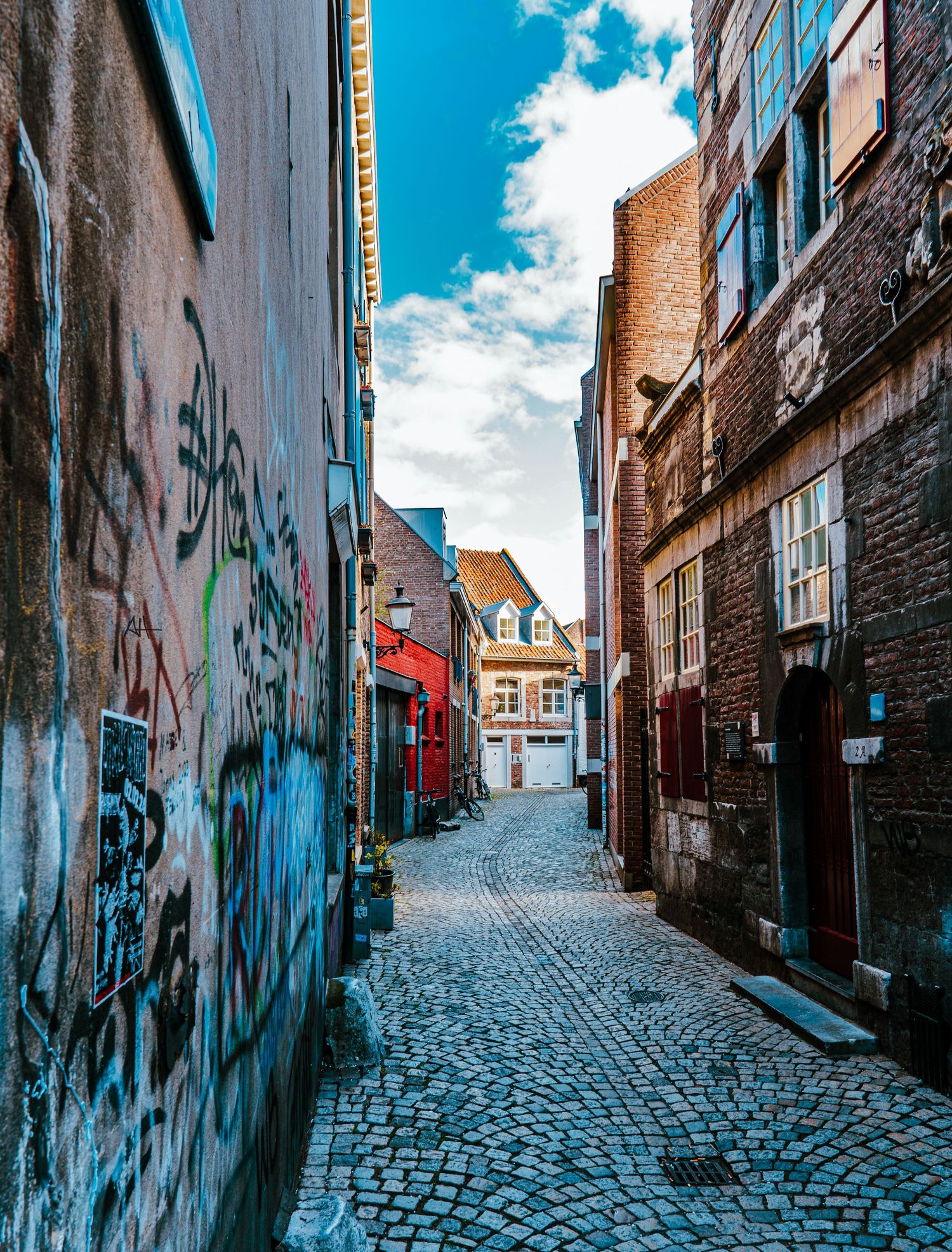 Street photograph of a narrow cobblestone alley lined with buildings in Maastricht.