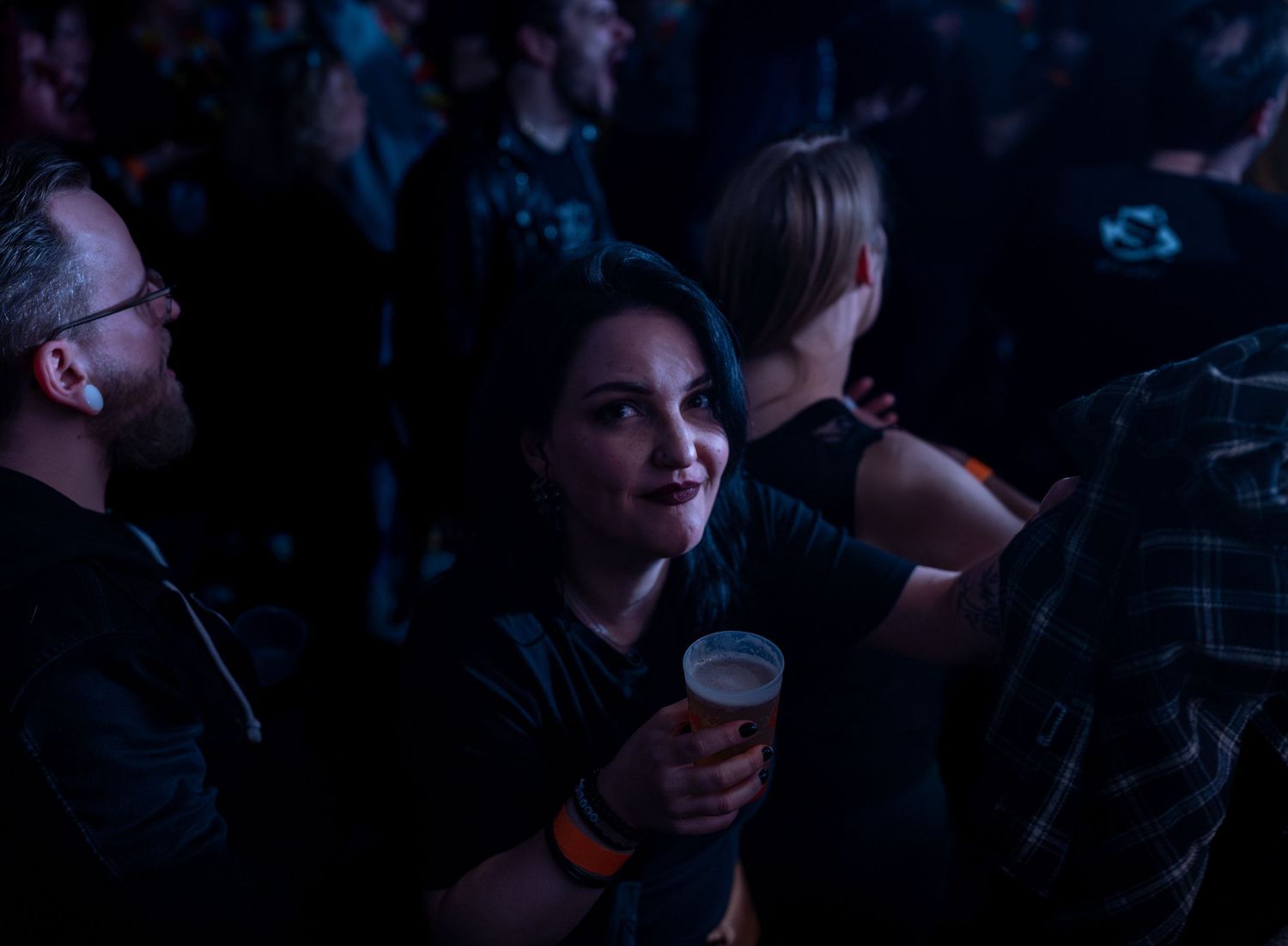 People enjoying drinks at a live music venue with blue lighting.