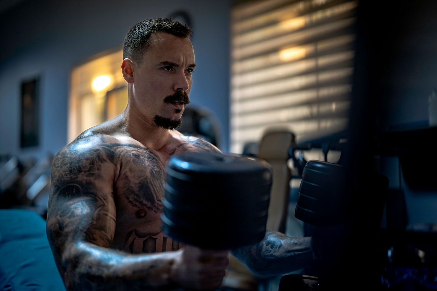 A muscular tattooed bodybuilder prepares to exercise.