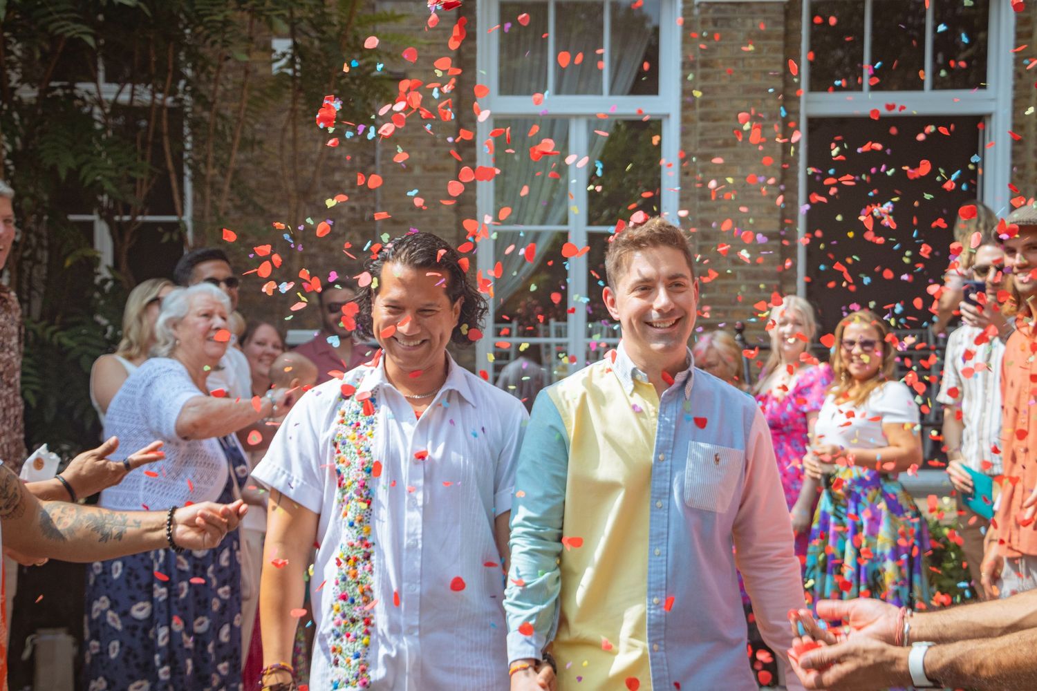 Candid LGBTQ+ wedding photo of two grooms celebrating with confetti after their ceremony in the Kitchener–Waterloo Region