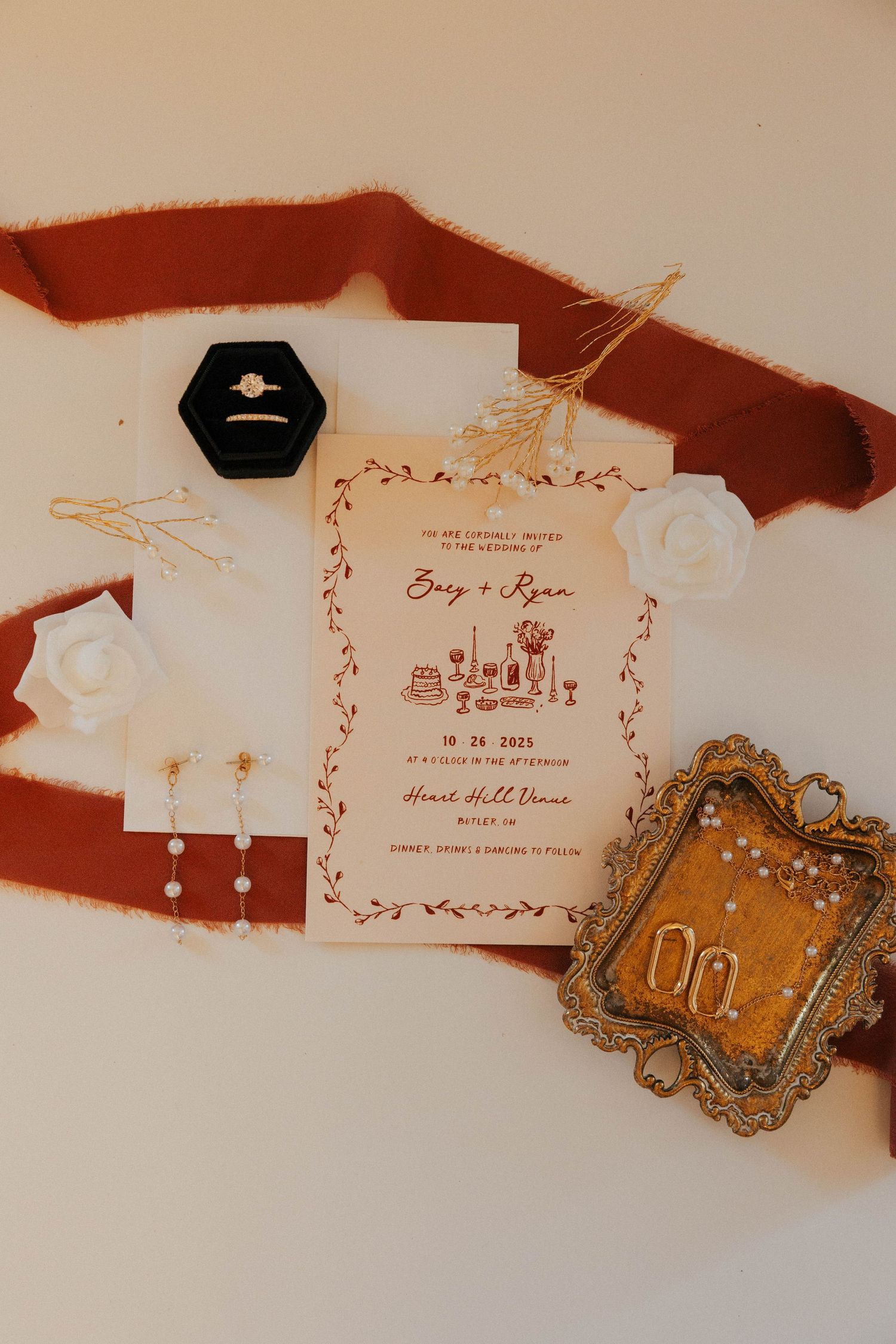 Elegant wedding invitation suite with red accents and ornate vintage-style details laid out on a light background.