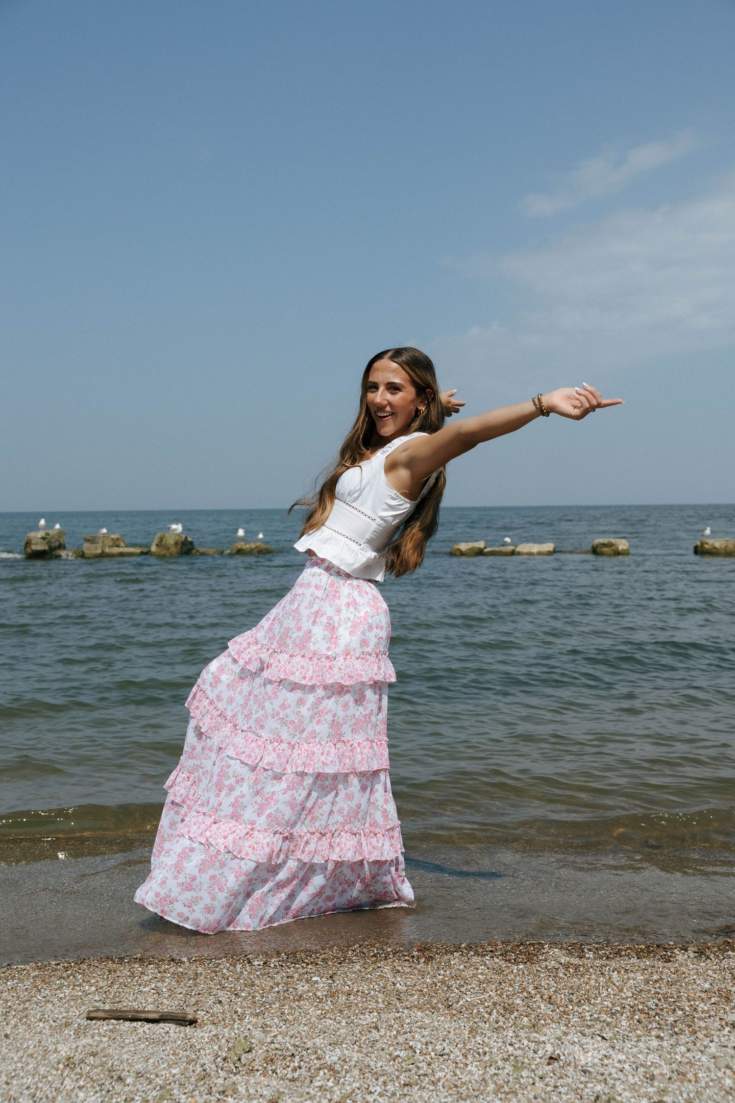 Person in flowing pink dress twirling on a beach with Lake Michigan in the background.