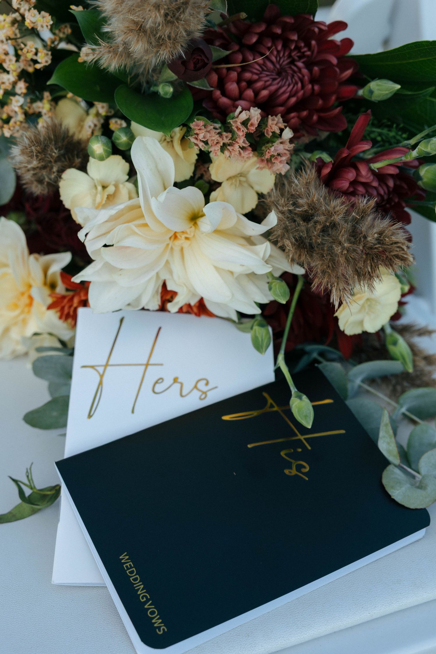 Elegant floral arrangement with white blooms and greenery atop black books.