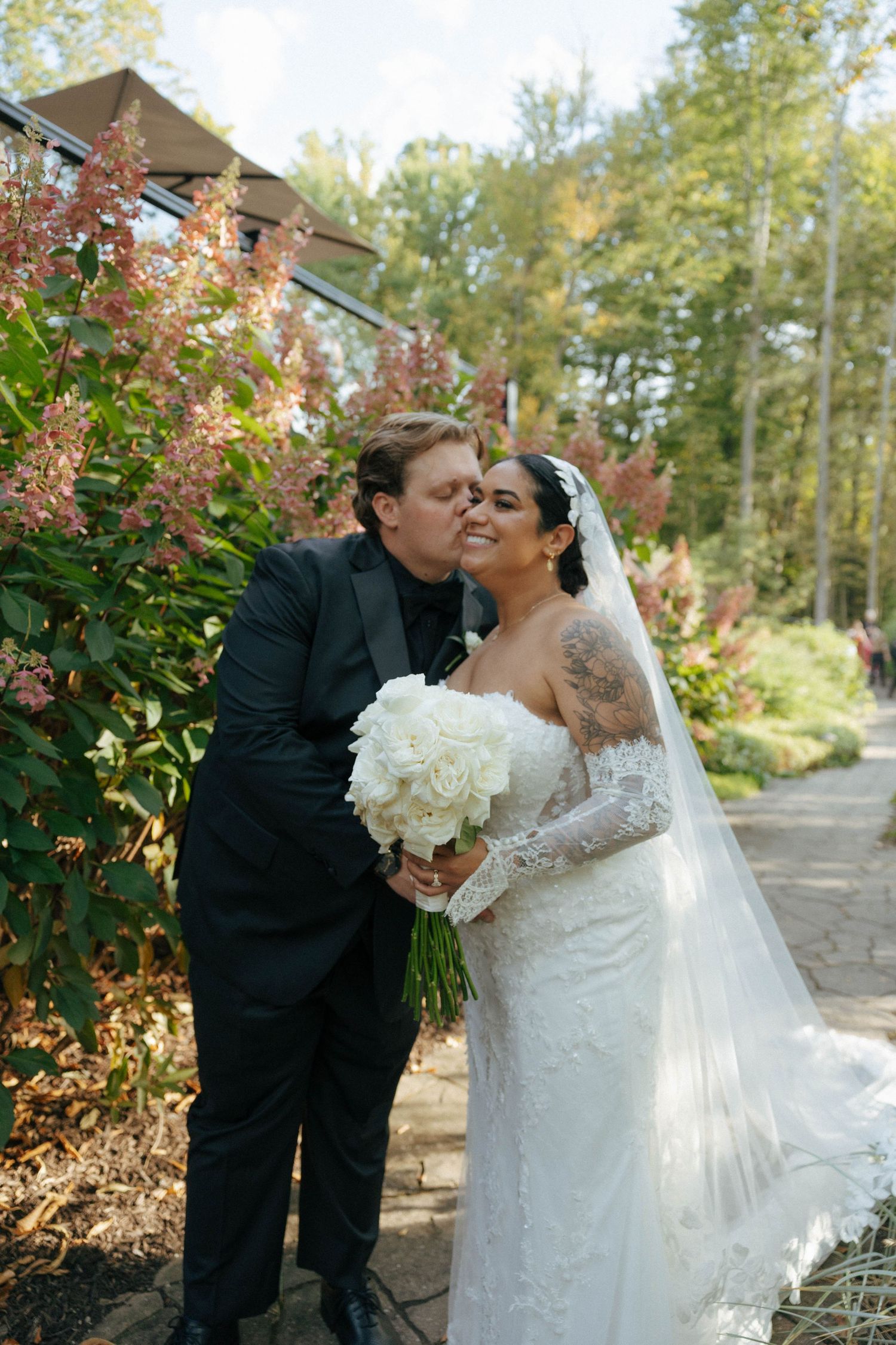 Romantic outdoor wedding portrait among fall foliage with white bouquet.