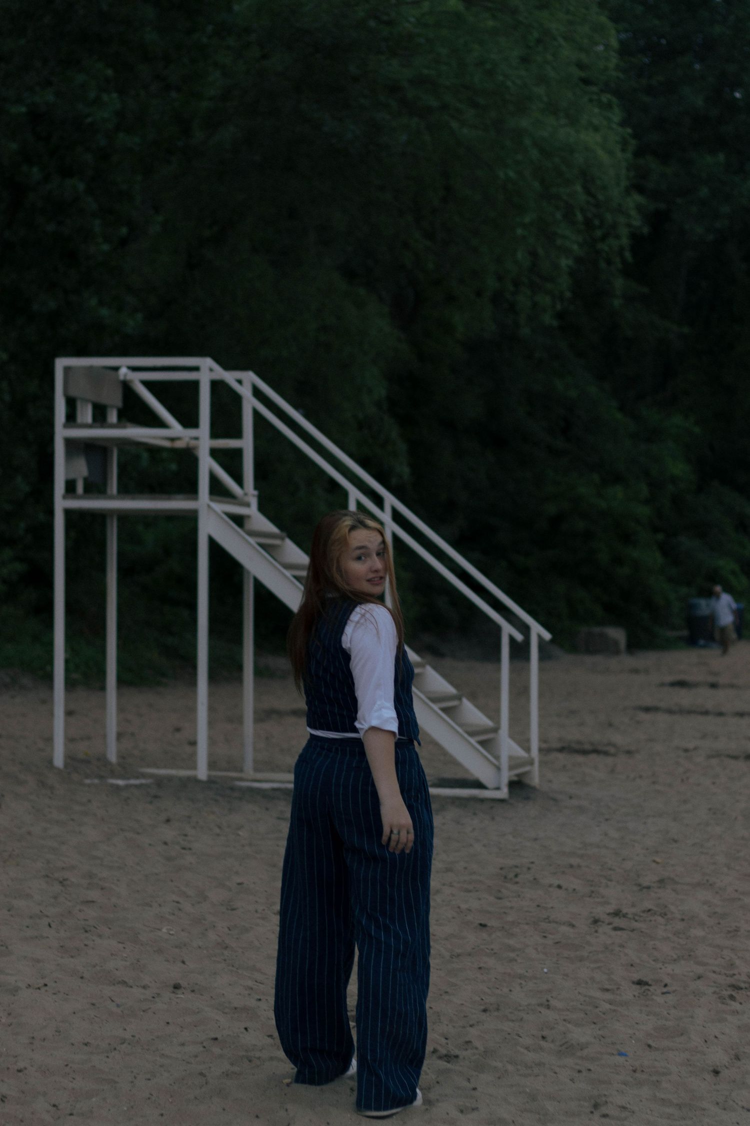 A series of dance movements performed in a sandy outdoor area with metal structures in the background.