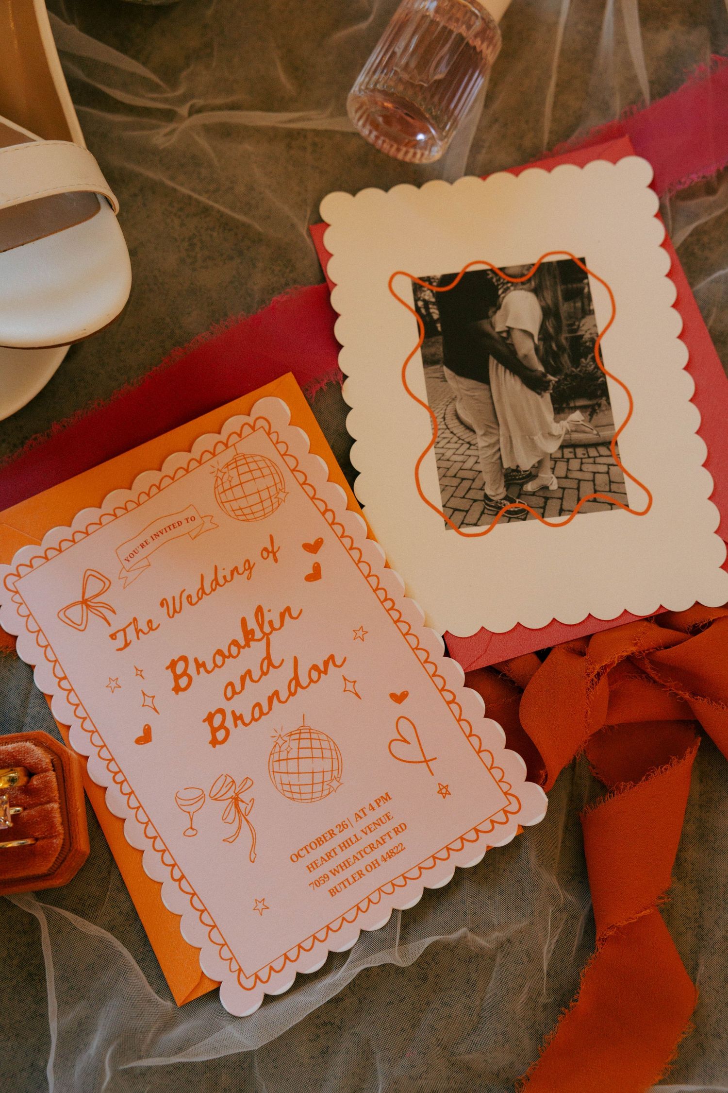 Orange and white decorative wedding invitation cards with scalloped edges laid out in a row.