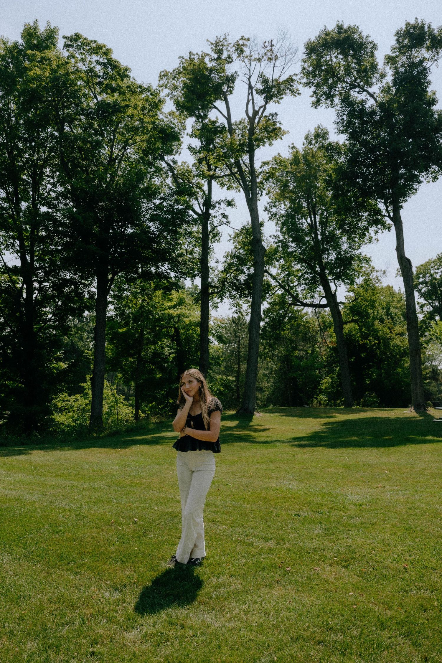 Figure moving gracefully across a grassy field surrounded by tall trees.