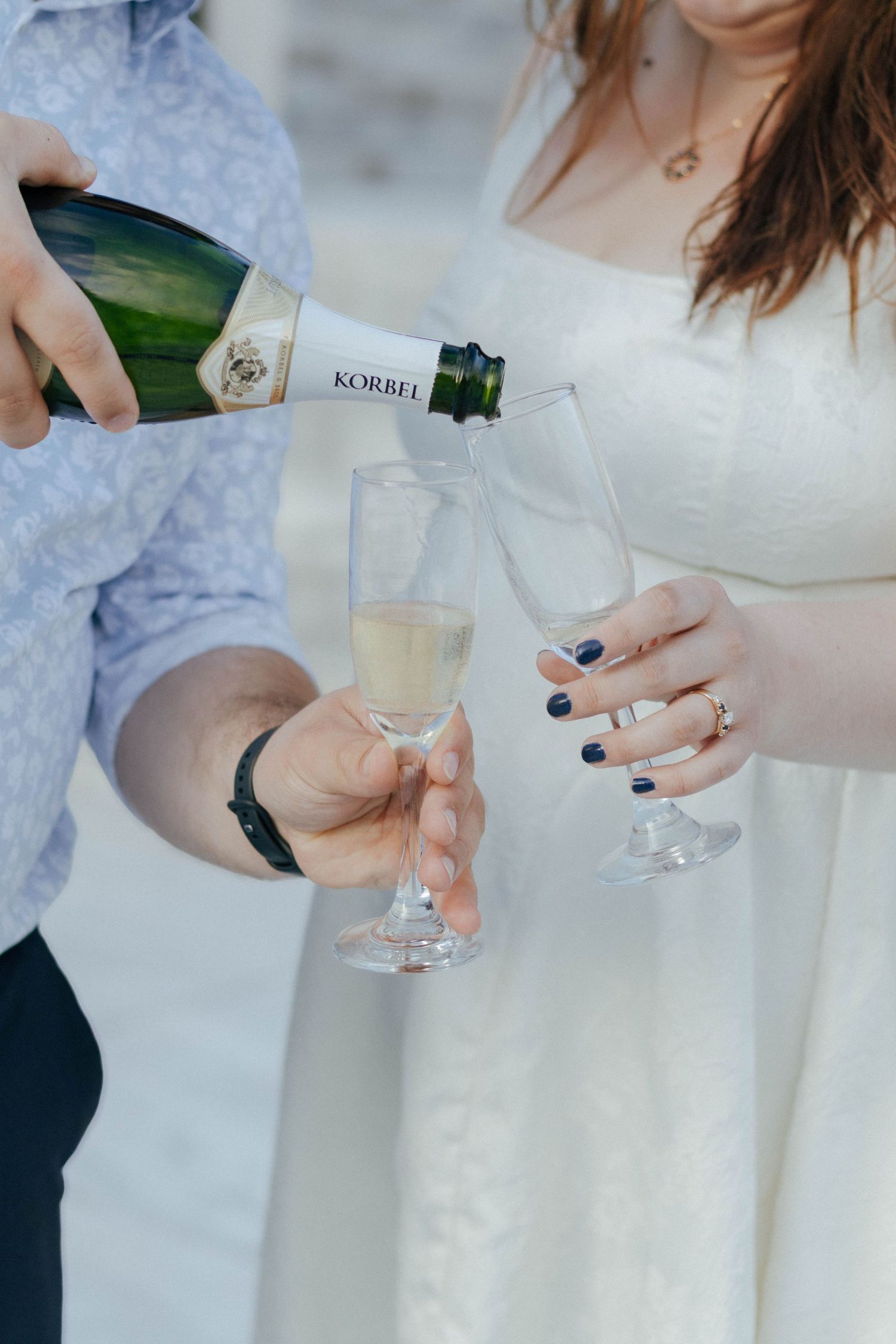 Hands pour champagne into elegant glasses during an outdoor celebration.