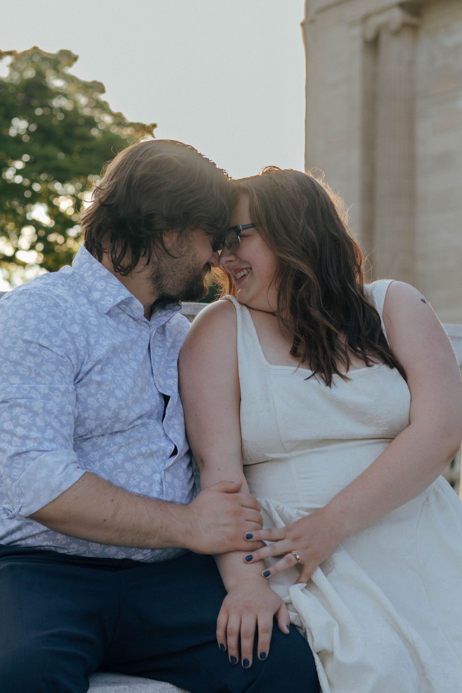 A couple shares an intimate moment while seated outdoors.