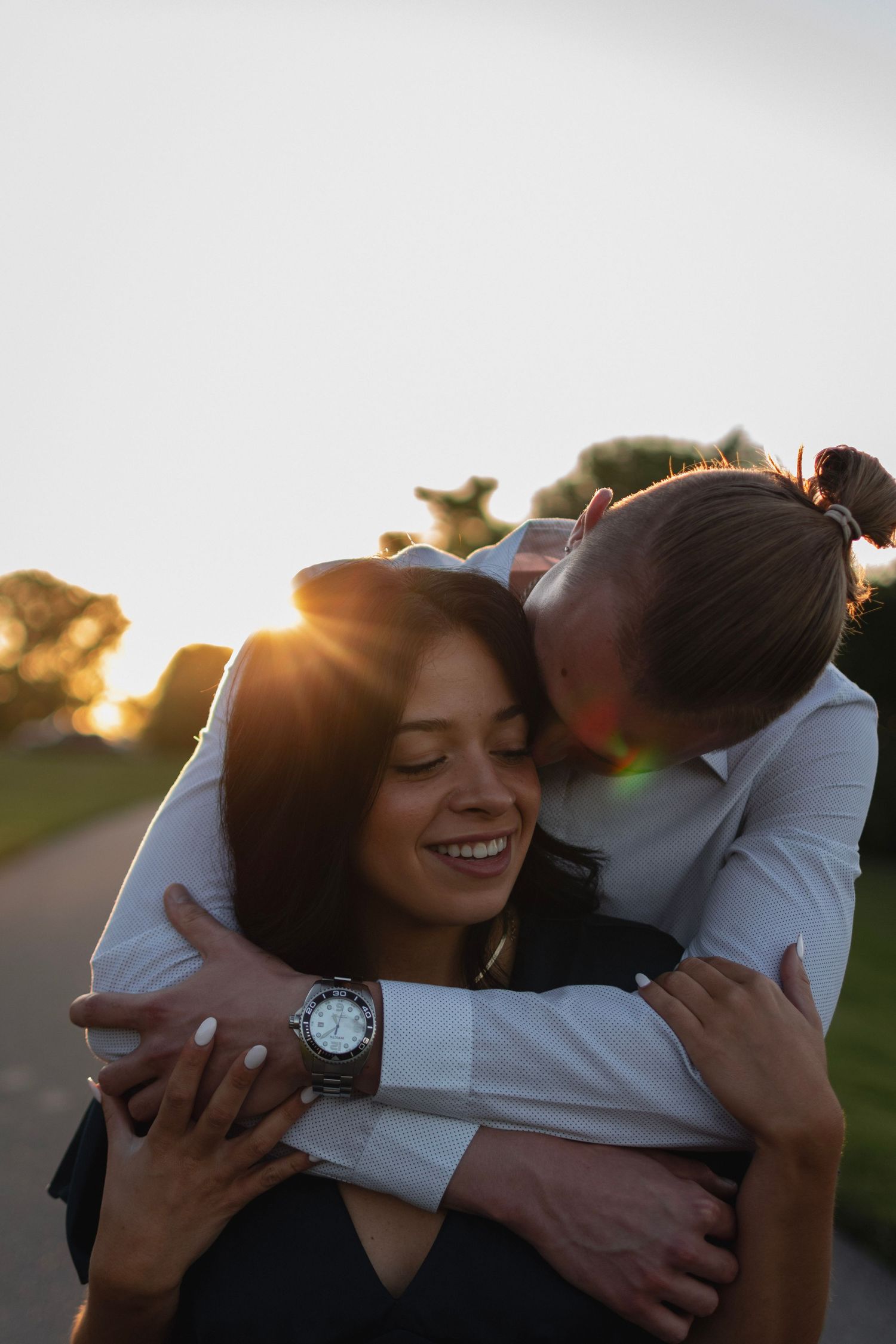 High-contrast photo of couple embracing at sunset on Durand Beach, Irondequoit NY. Dramatic engagement portrait.