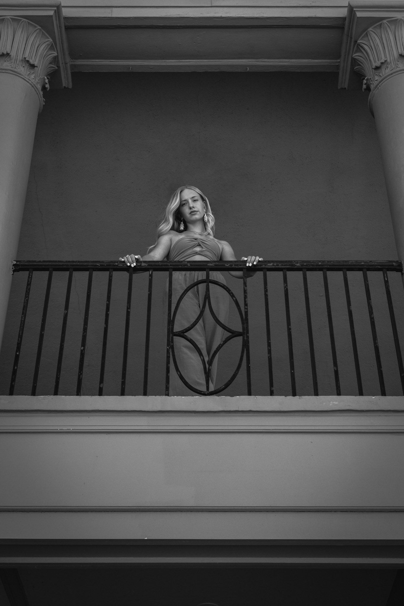 B&W architectural portrait on Ontario Beach Bath House balcony in Rochester, NY, framed by classical columns and wrought iron railing.