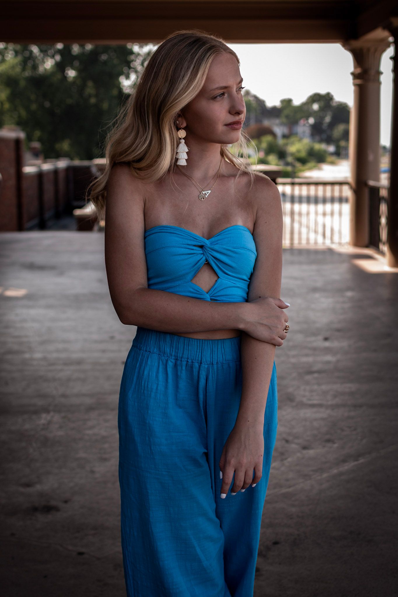 Moody senior portrait at the Ontario Beach Park Bath House in Charlotte, NY, with a blue outfit against industrial brick and stone.
