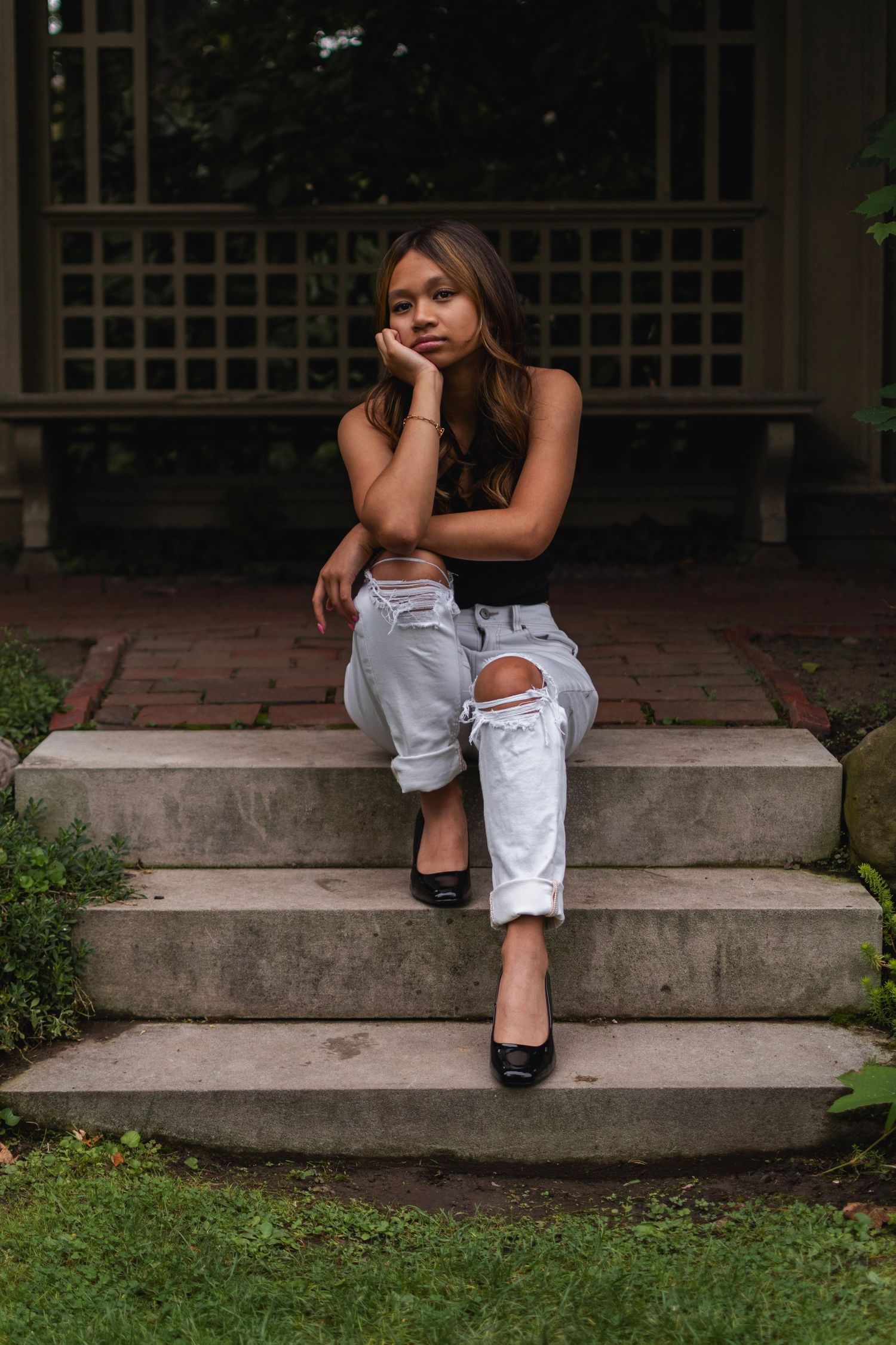Moody color senior portrait of teenager sitting on steps in the Eastman House gardens, Rochester NY.