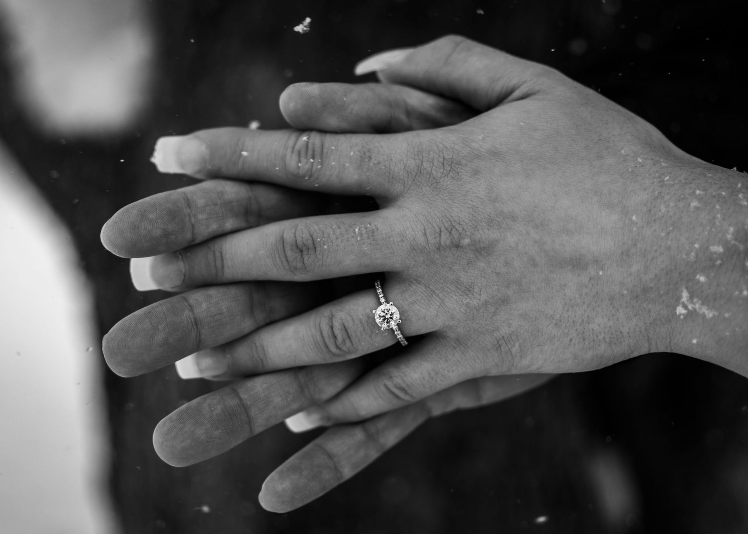 B&W high-contrast detail photo of engagement ring on a couples hands in snow, captured in January at Webster Park, NY. Cozy winter session.