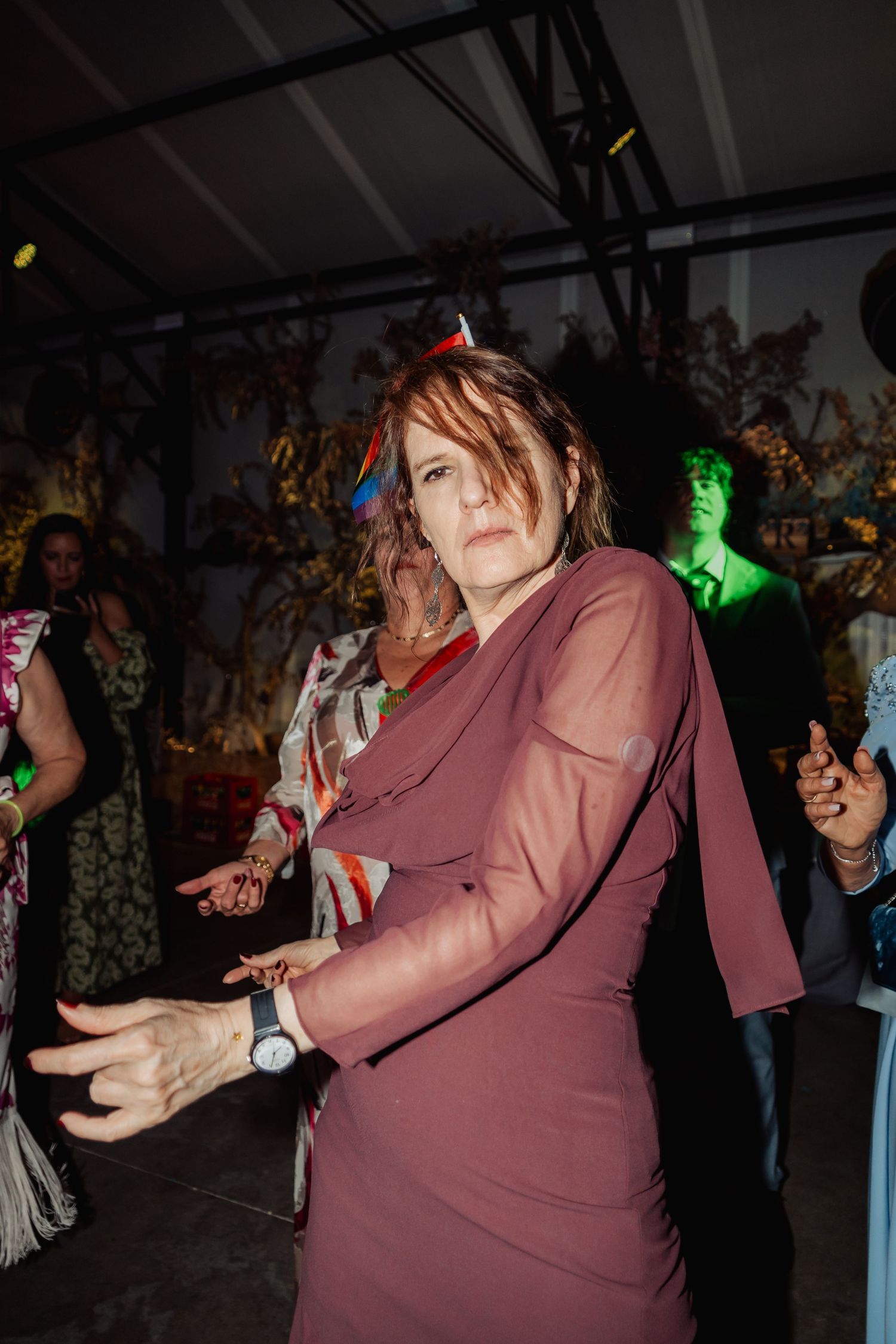 Woman in mauve long-sleeve dress dancing expressively at a lively evening party event.