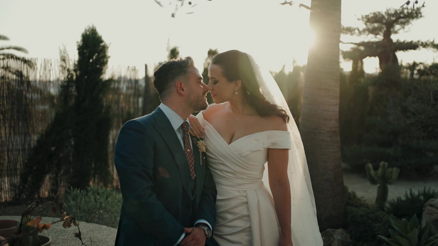 Bride and groom share a golden hour kiss in a lush garden on their wedding day.